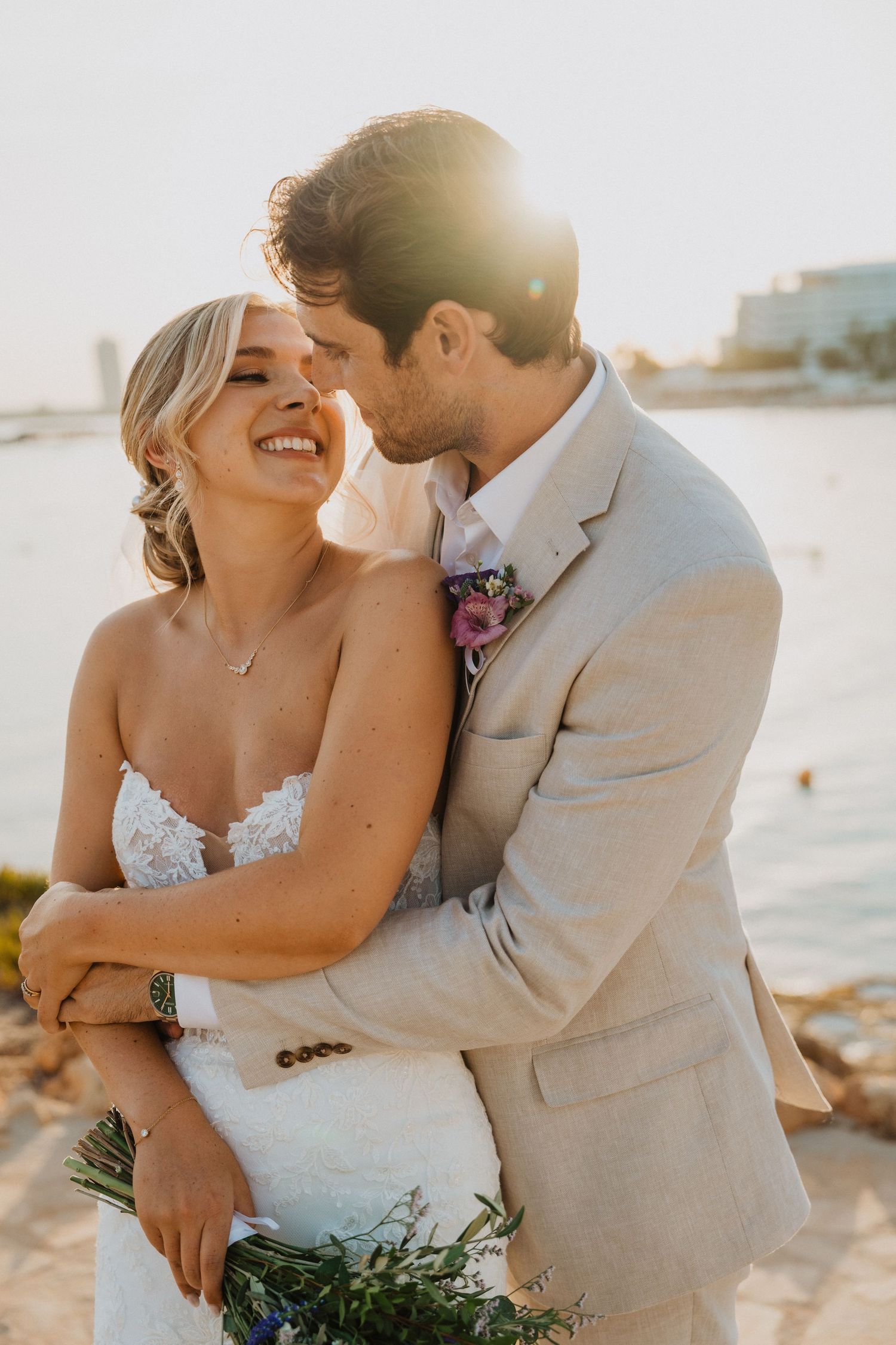Sun-kissed wedding portraits capture tender moments between newlyweds on a coastal setting.