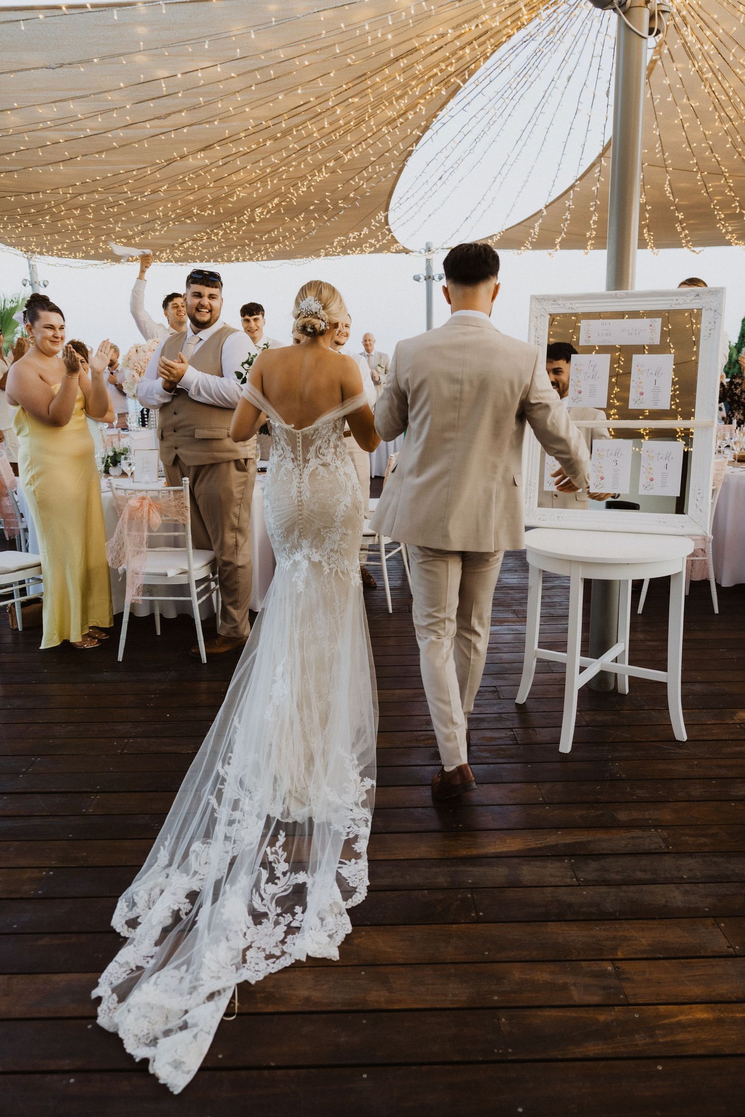Reception setup with white chairs and tables under draped fabric ceiling.