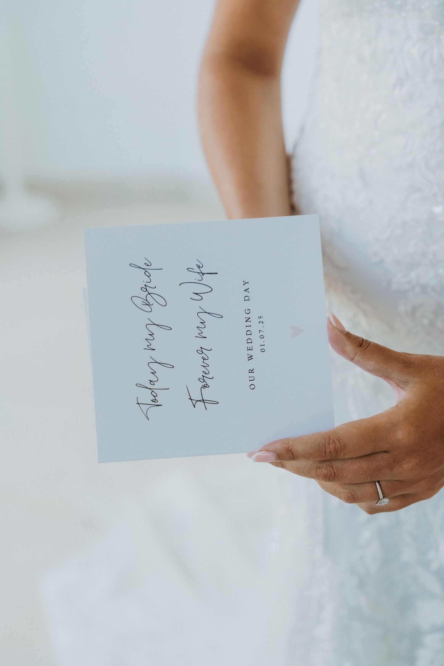 Close-up view of hands holding a white paper note against a soft blurred background.