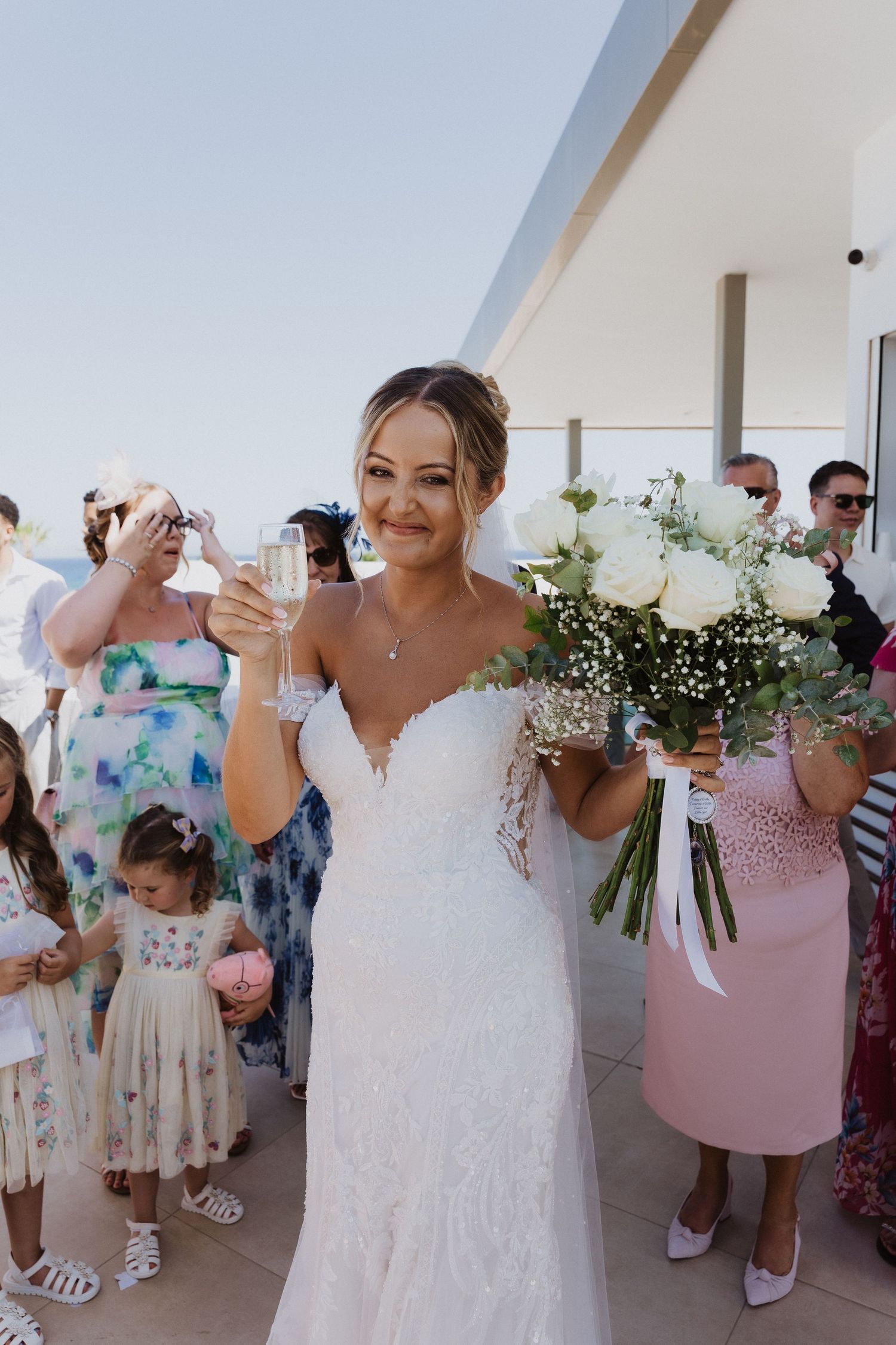 Wedding party celebrates in a bright venue with pink bridesmaid dresses and white floral bouquets.