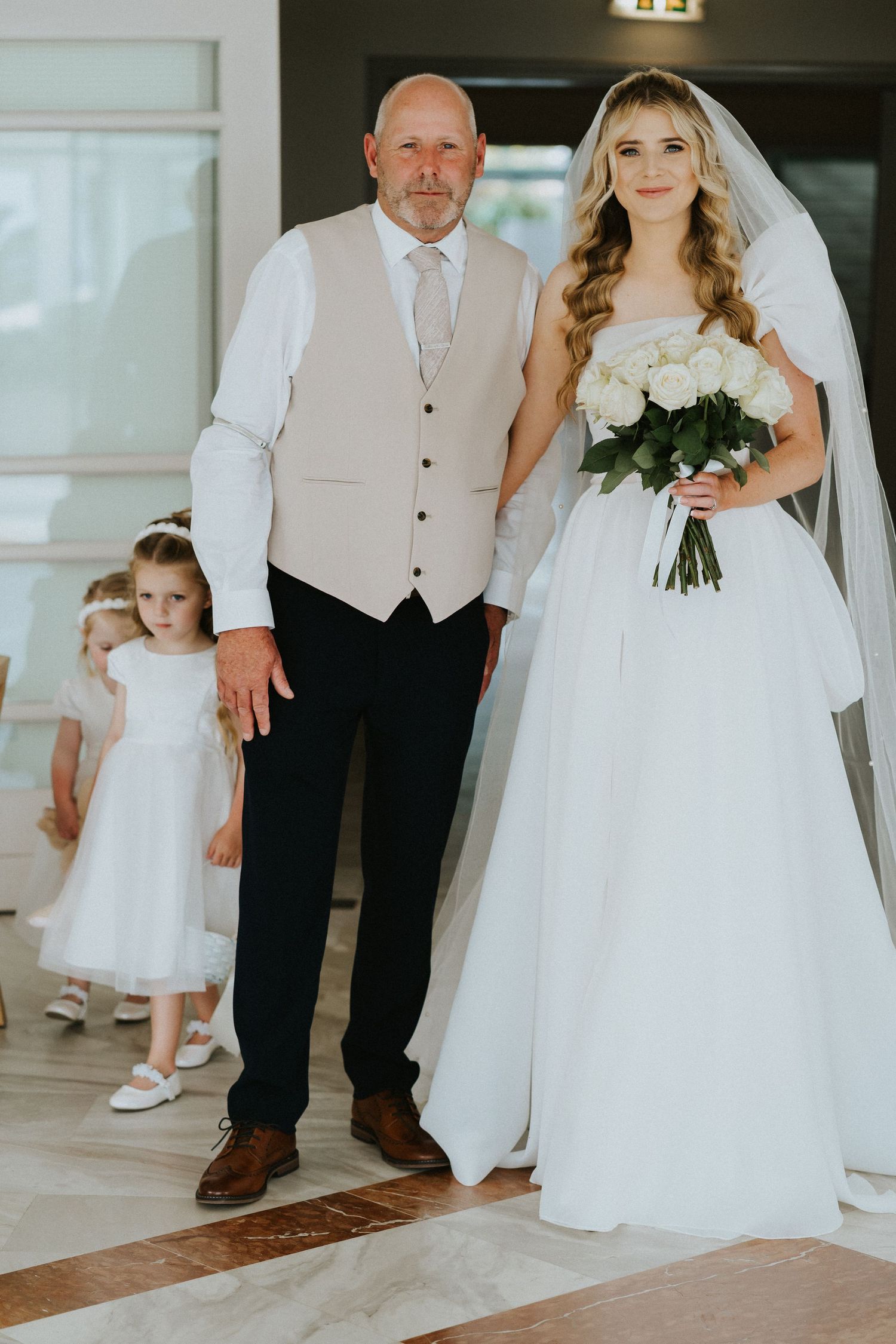 Wedding party members posing in formal attire with a bouquet of white flowers.
