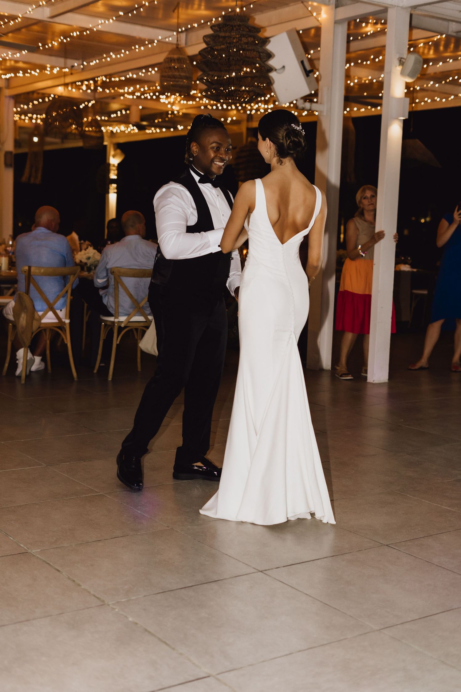 Romantic first dance moment captured at elegant wedding reception with string light backdrop.