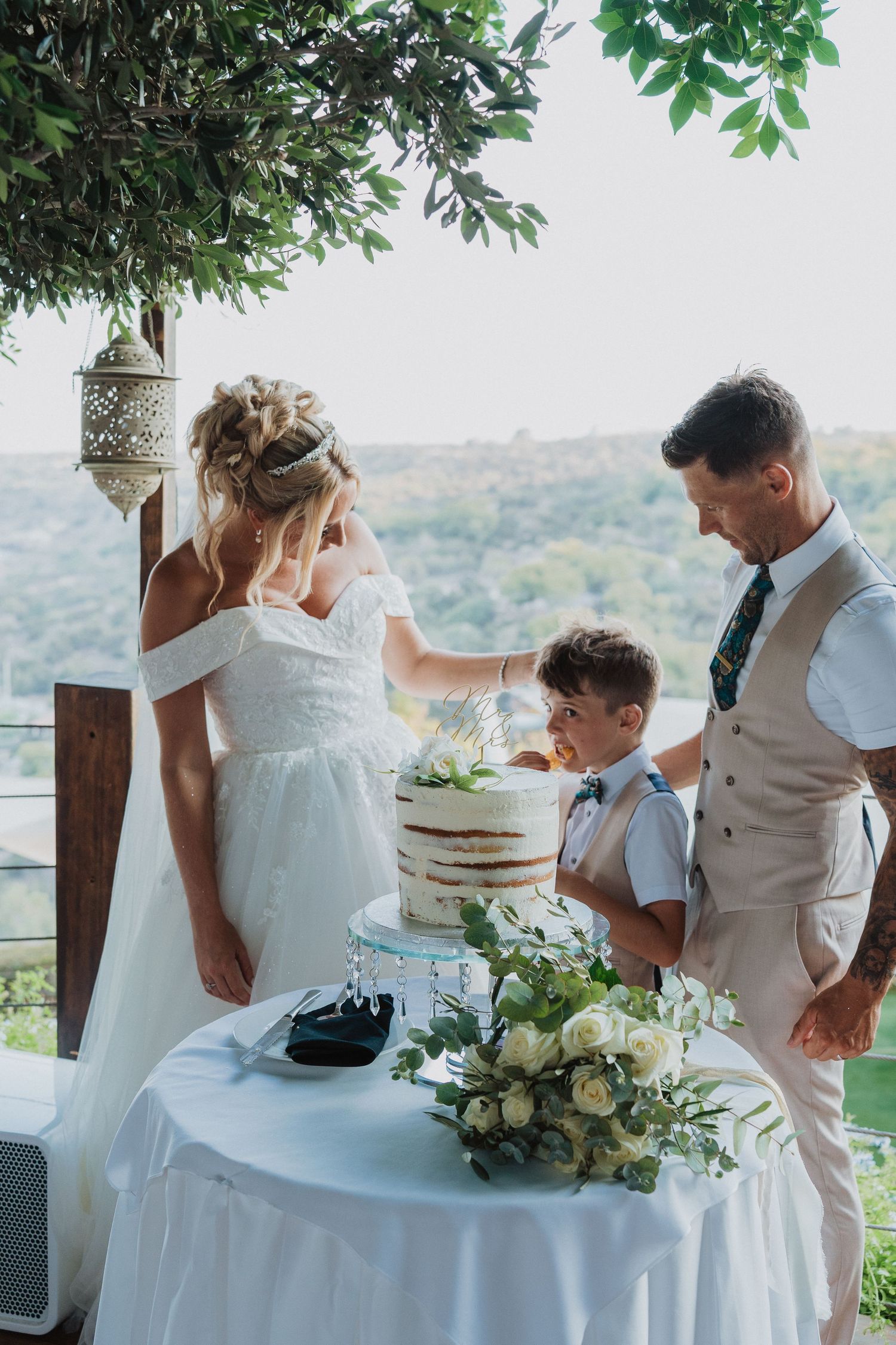 Intimate cake cutting moment at outdoor reception with scenic valley views.