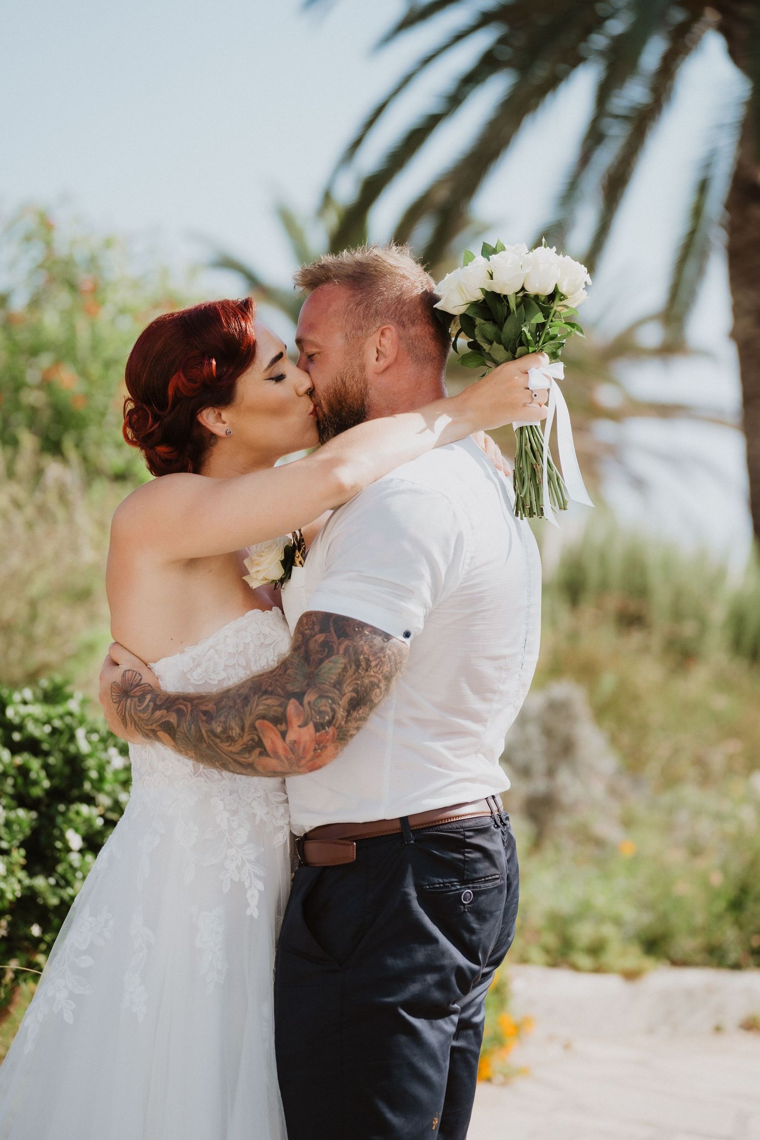 An intimate wedding moment shared between newlyweds in a lush tropical garden setting.