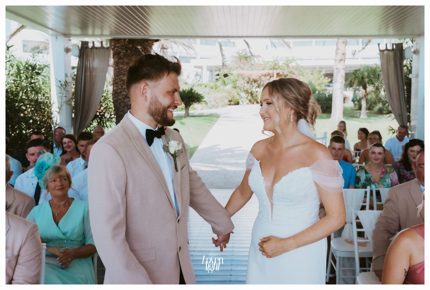 Joyful exchange of vows during a wedding ceremony under a white covered pavilion.