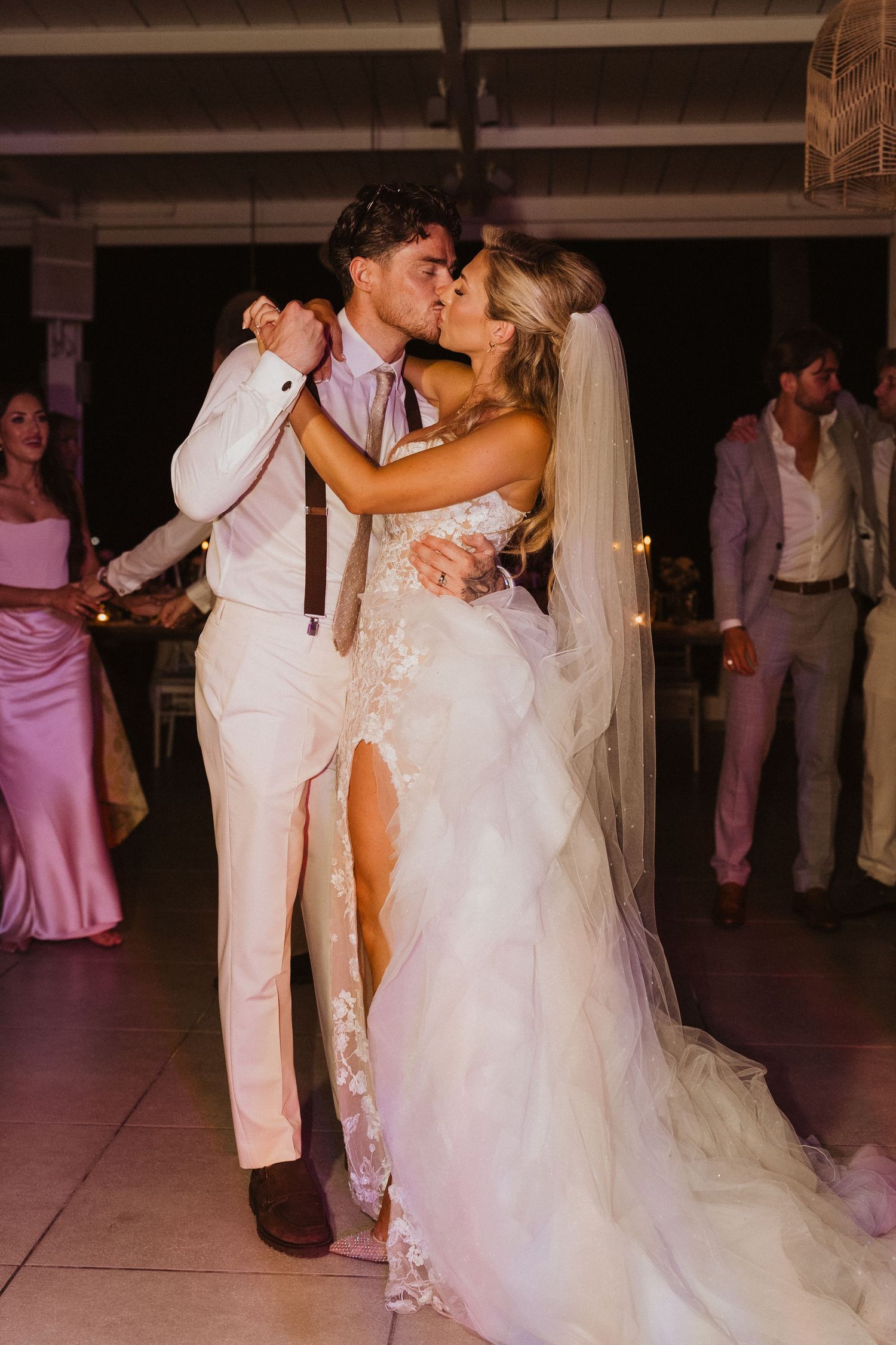 A couple shares their first dance at a wedding reception while guests watch from the dance floor.