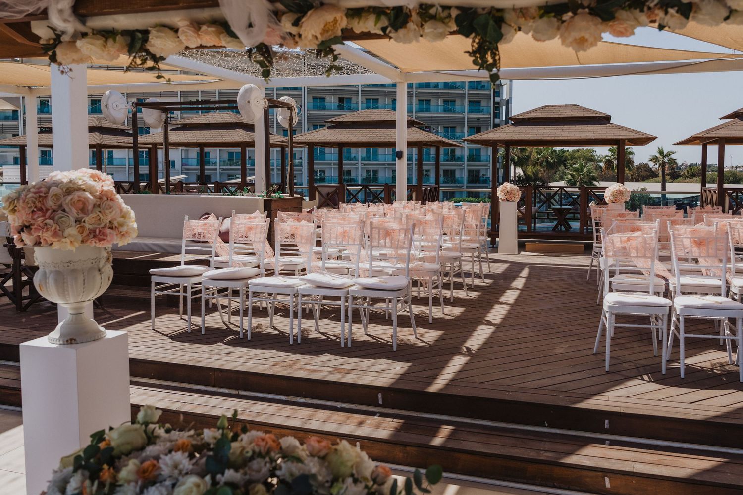 Outdoor wedding ceremony setup with white chairs and floral arrangements facing the ocean.