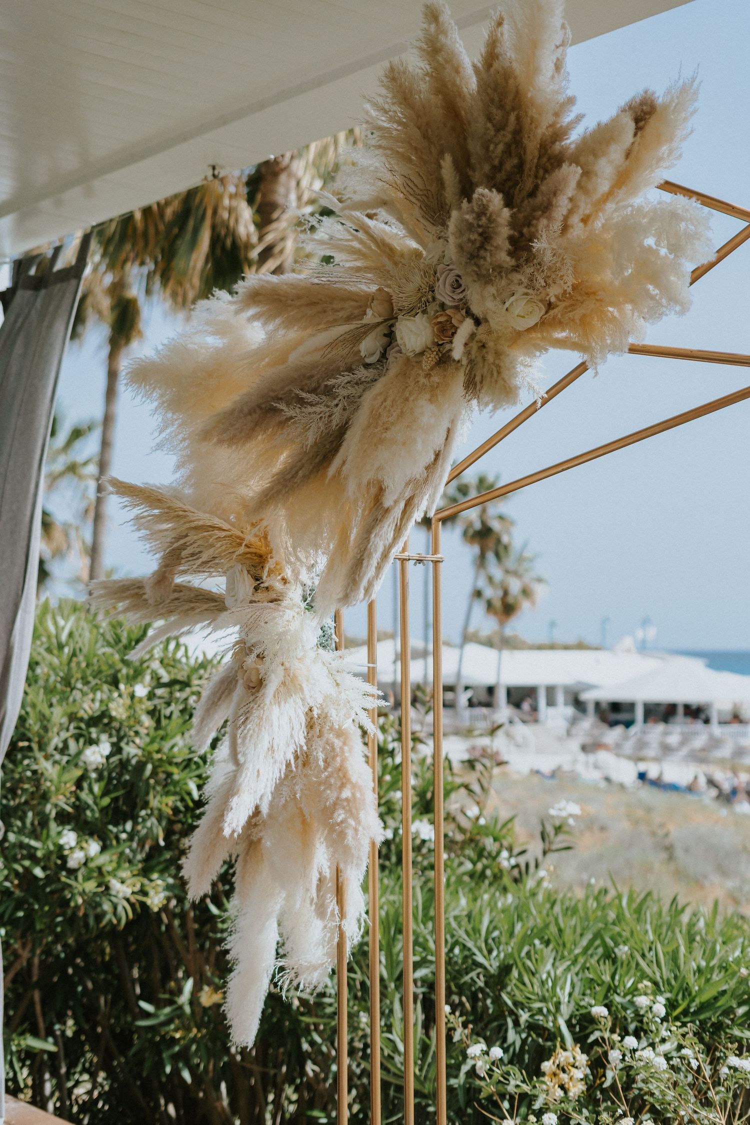 Modern wedding decor featuring dried pampas grass arrangements on gold geometric stands.