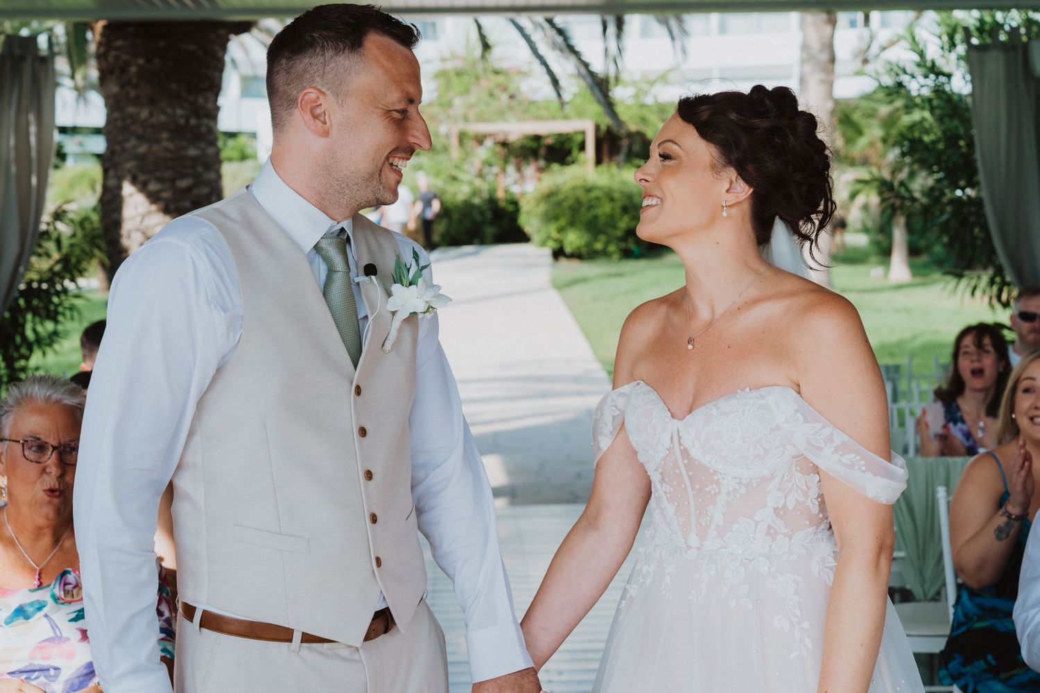 Joy and laughter between a couple in wedding attire during a sunny outdoor ceremony.