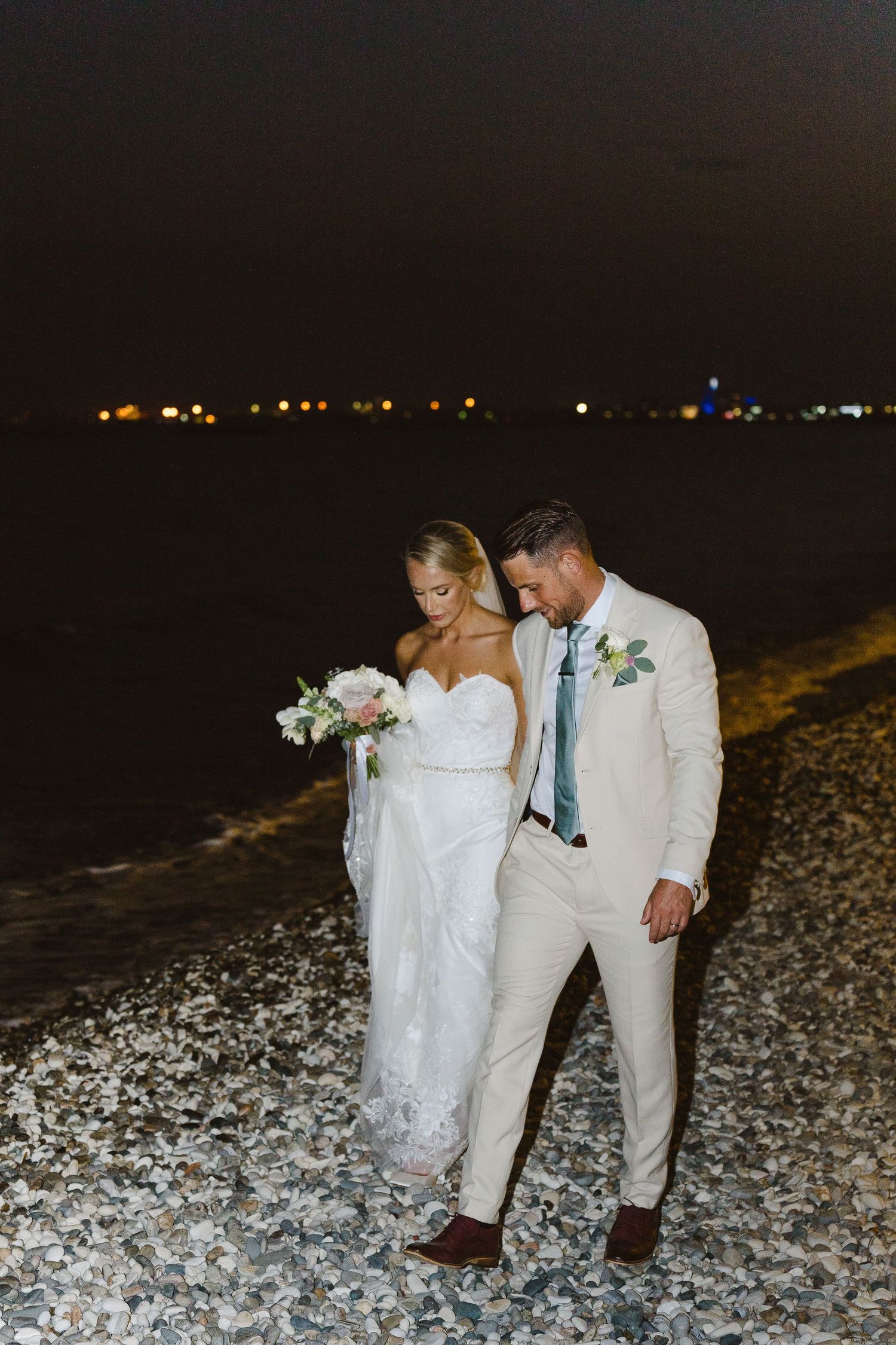 Beachside wedding photography with city lights glowing in the background at night.