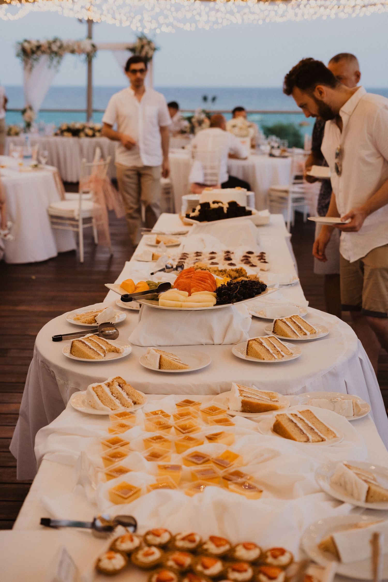 Elegant wedding buffet table with appetizers and hors d'oeuvres displayed on white linens overlooking the ocean.