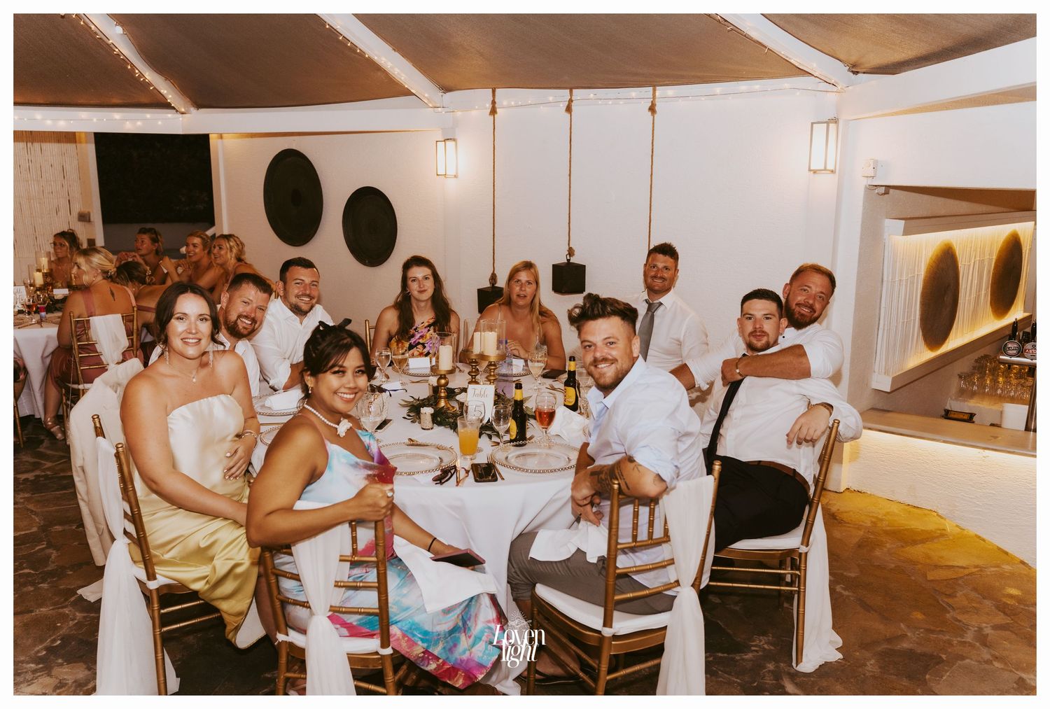 Wedding reception guests seated at round tables enjoying dinner in an elegant indoor venue.