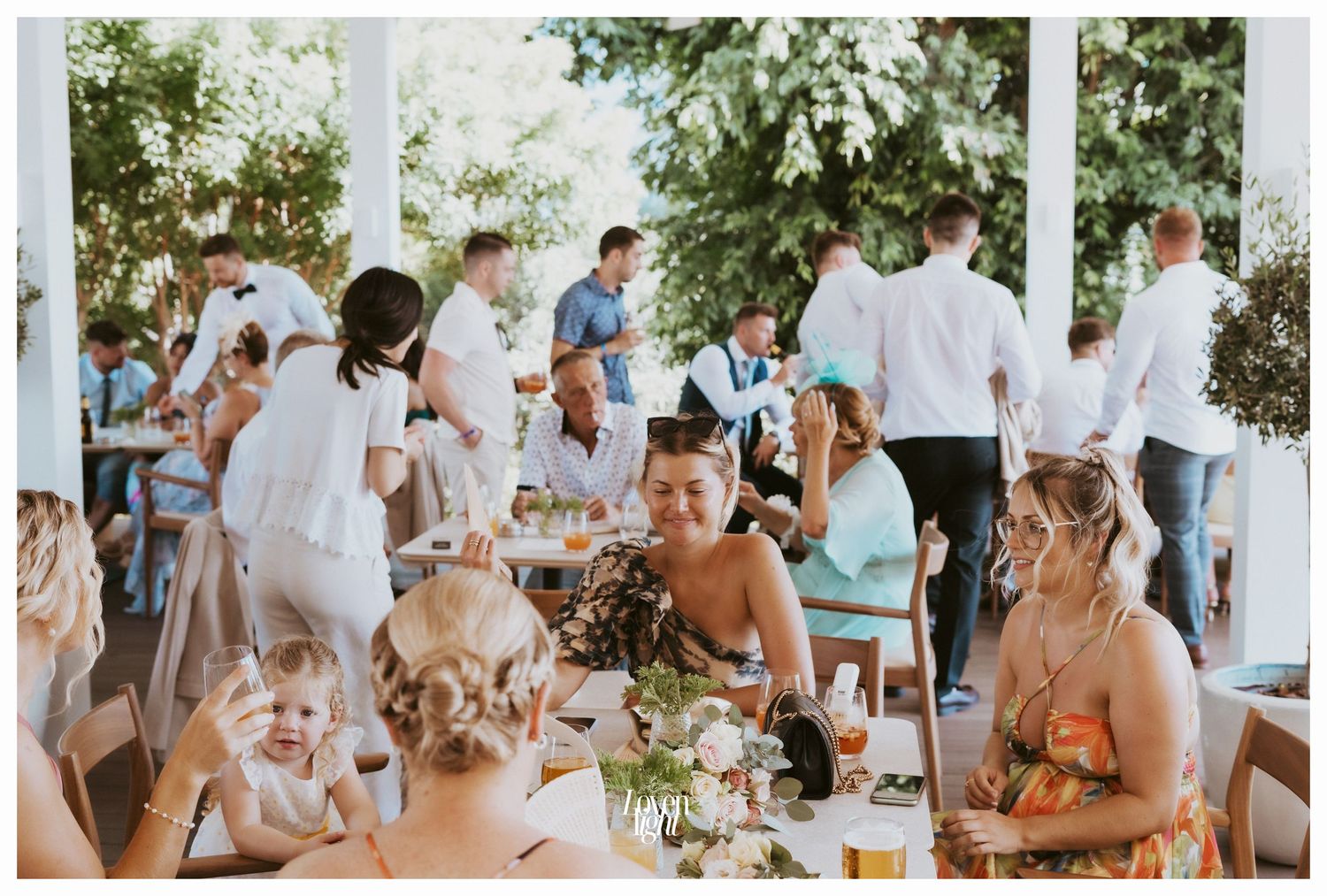 A casual outdoor wedding reception setting with guests seated at decorated tables.