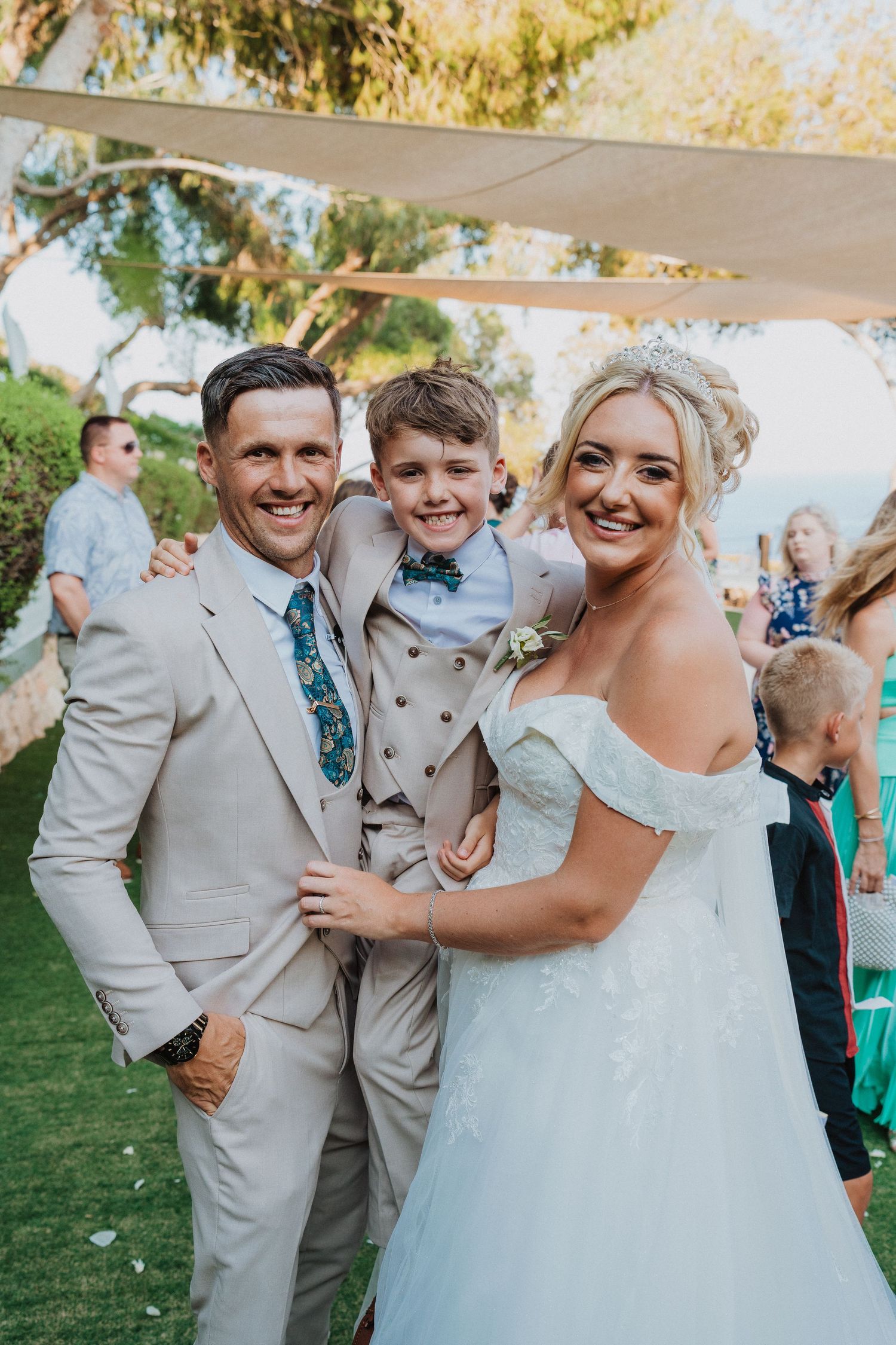 Happy wedding portrait of couple with young boy in matching formal attire.
