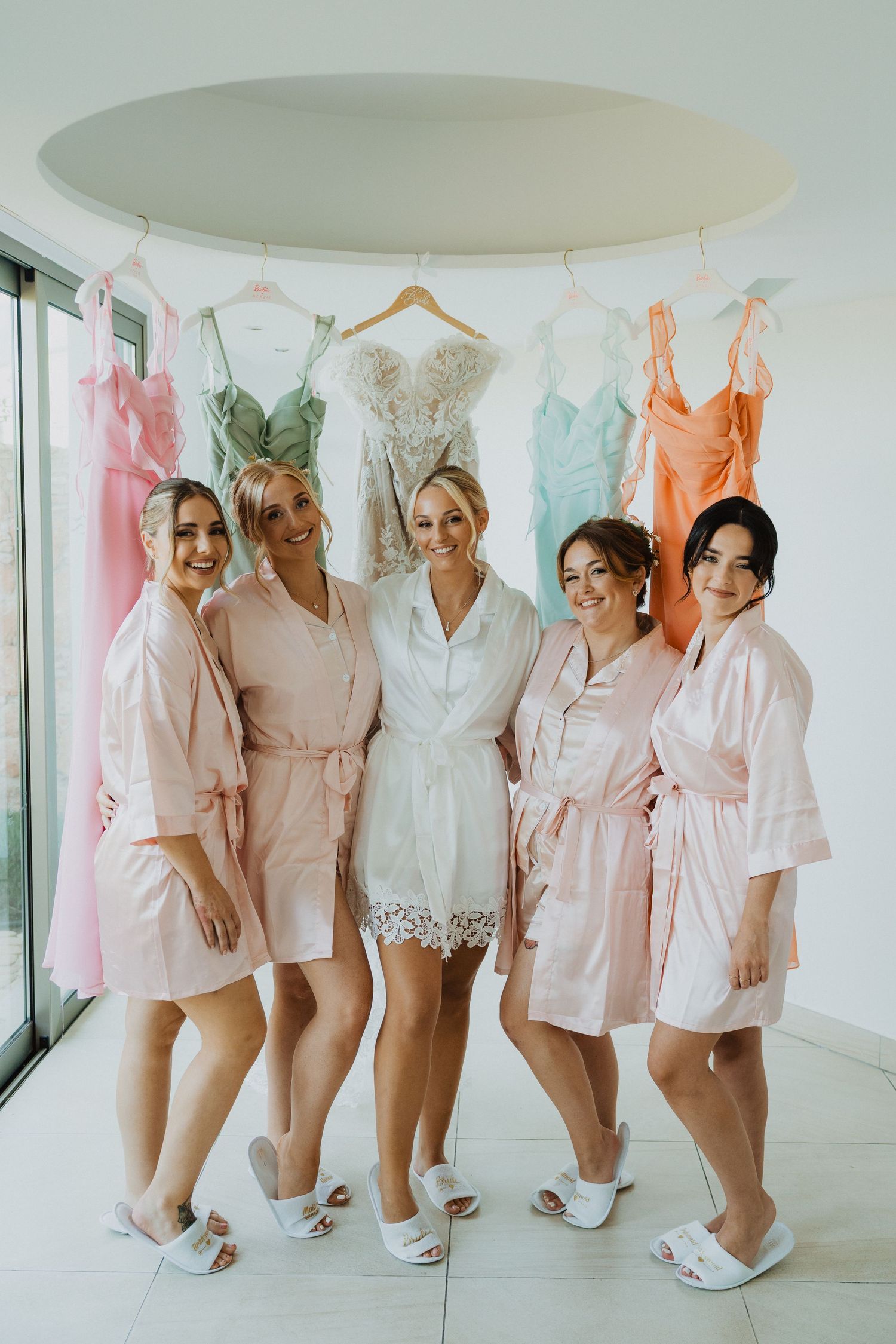 A group wearing matching pink robes and white slippers poses together before a wedding.