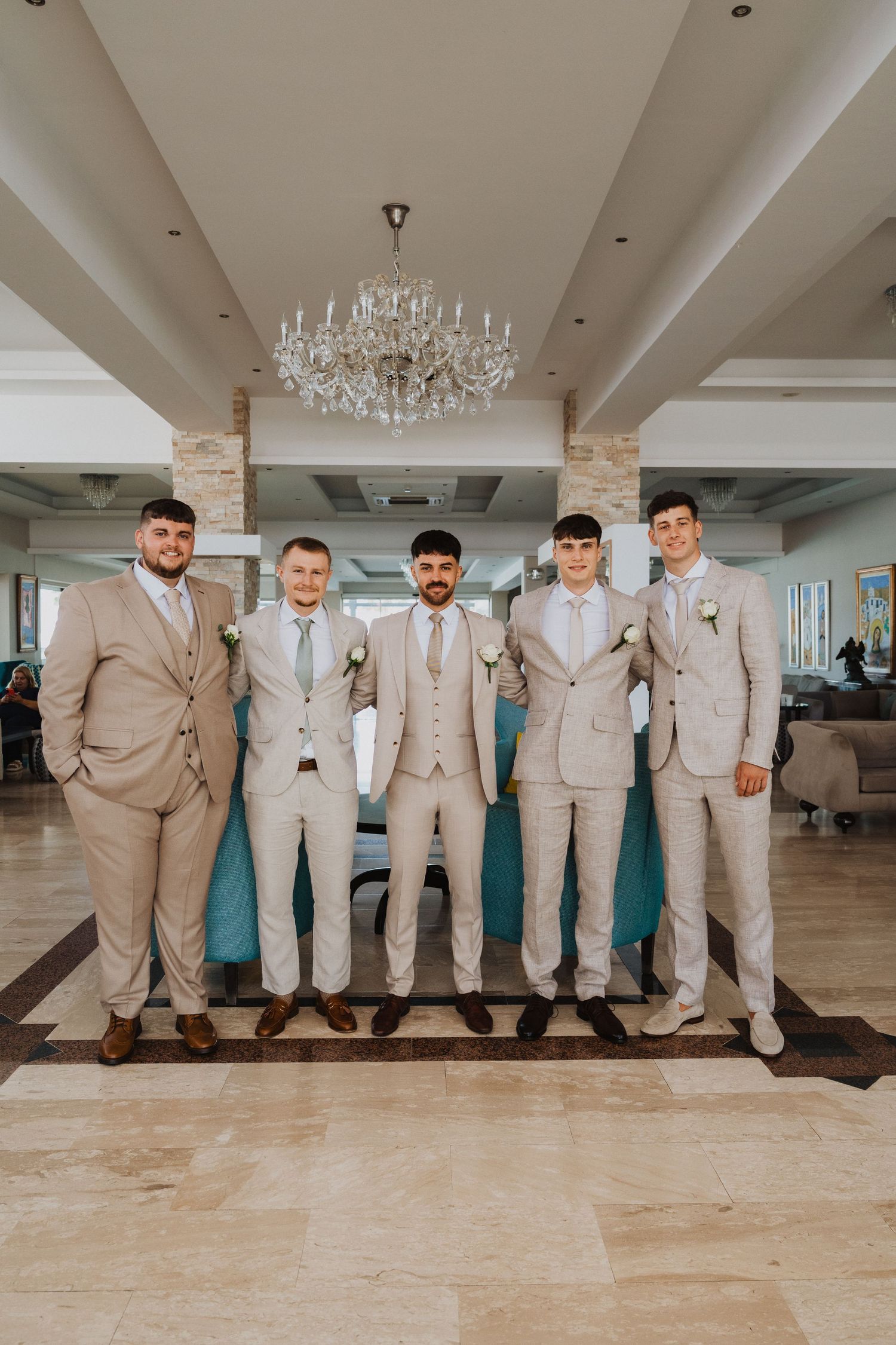 Groomsmen in matching beige suits standing in line at wedding venue.