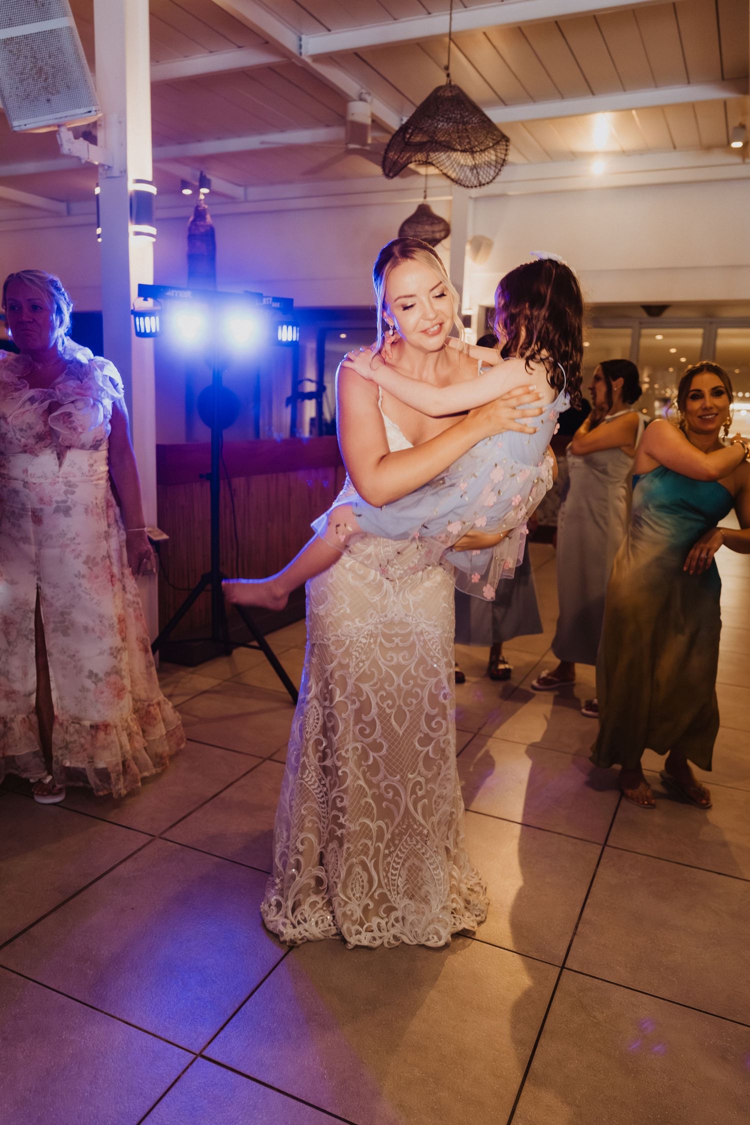 Wedding reception dance floor with couples dancing under purple mood lighting.