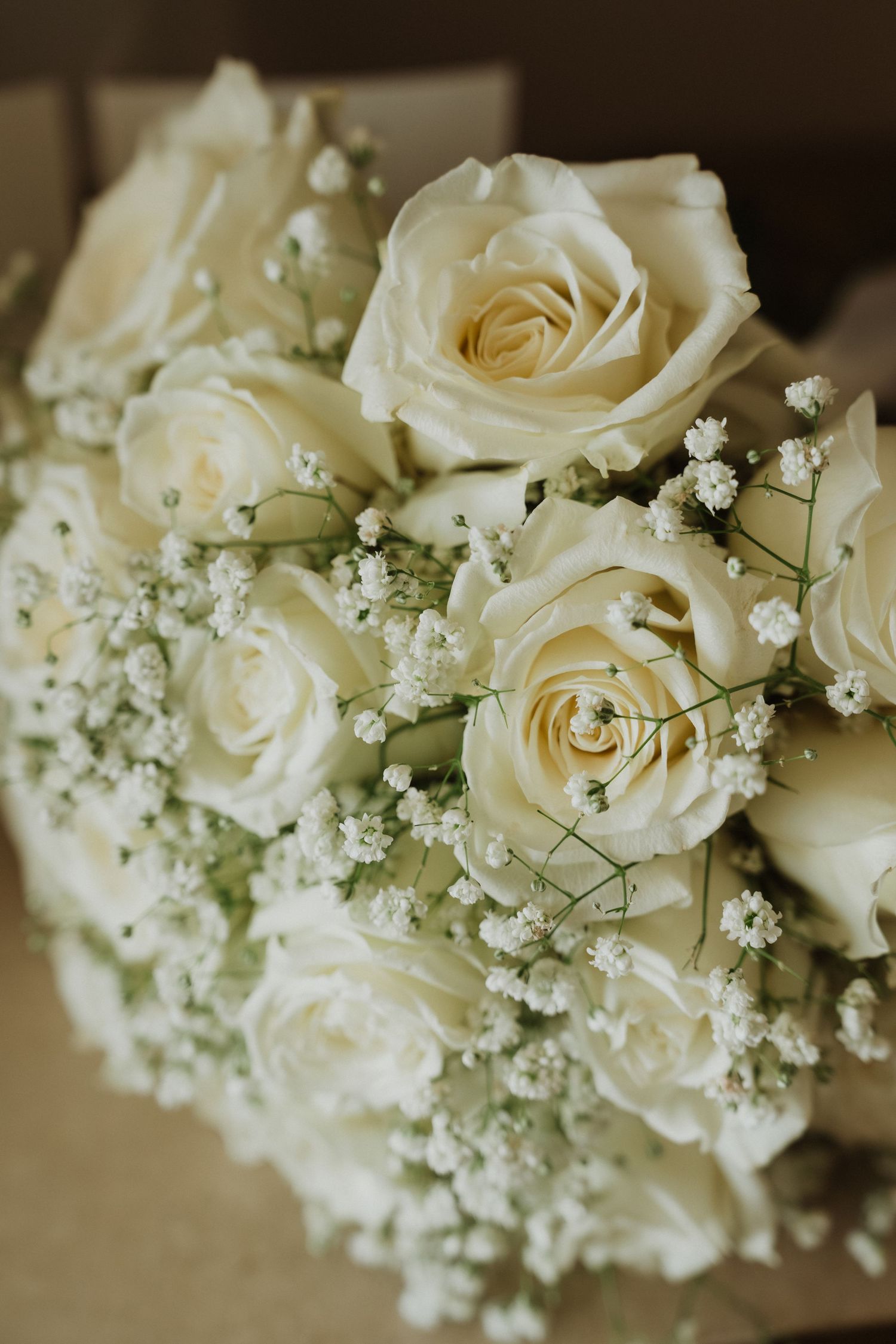 Elegant white roses and baby's breath flowers arranged in a delicate wedding bouquet.