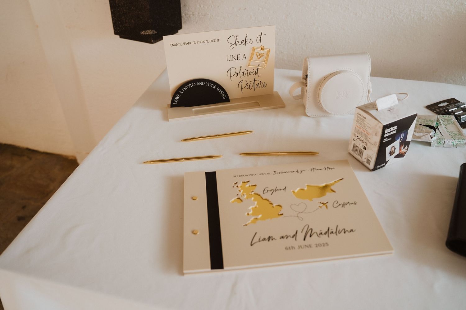 Wedding guest book table with gold Cyprus map design, Polaroid camera, and personalized stationery.