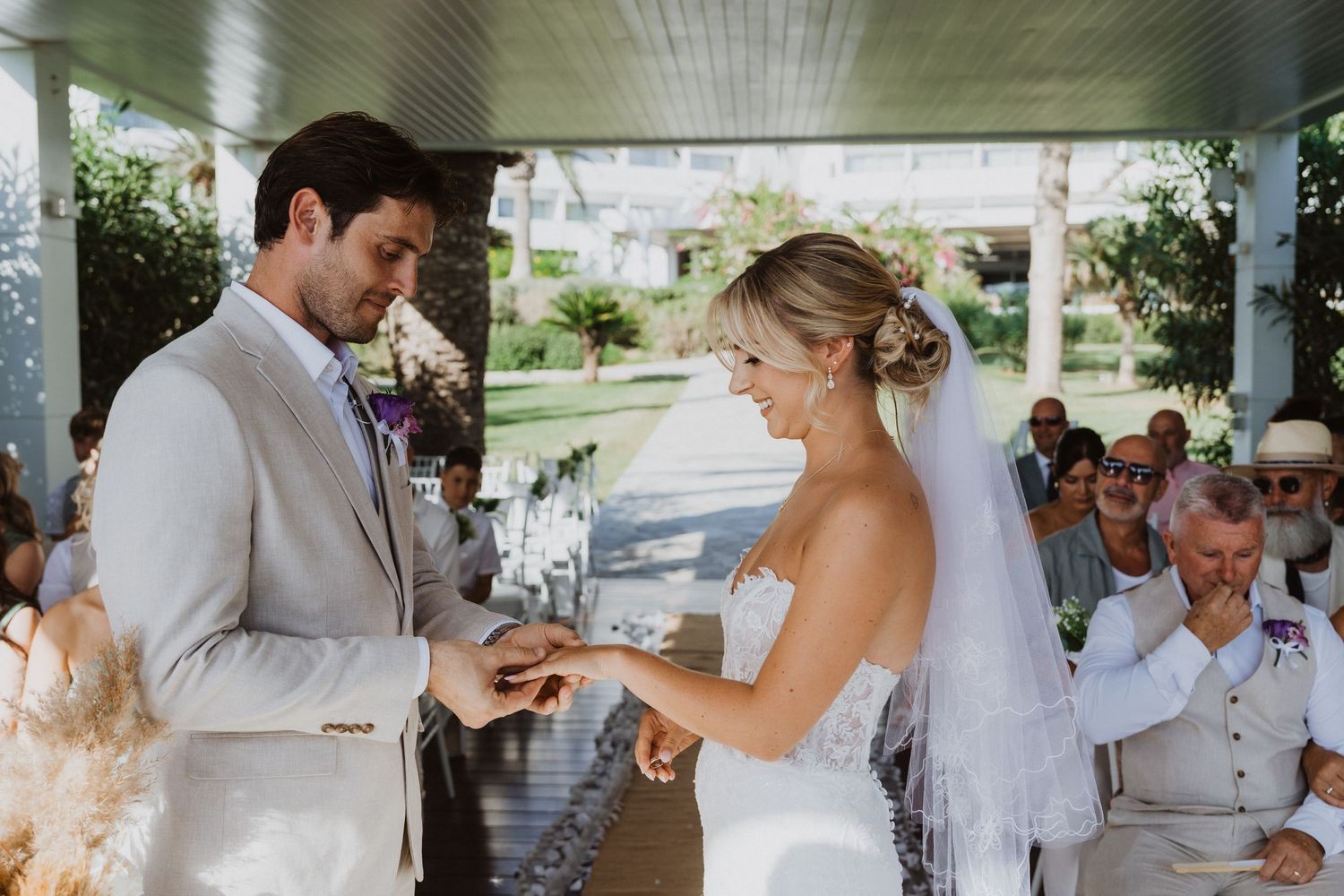 Wedding guests celebrate and toast during an outdoor reception under palm trees.