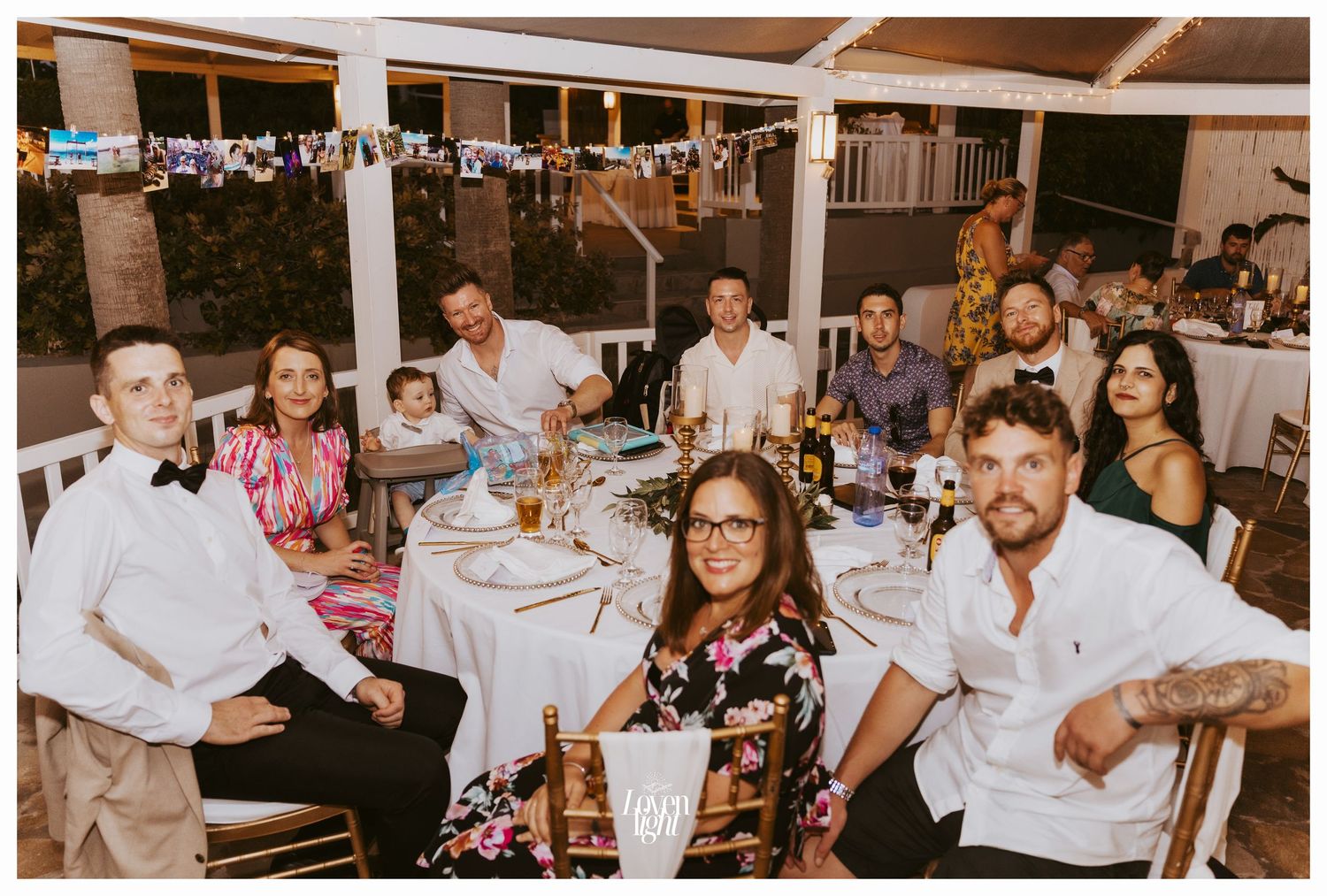 Wedding guests seated at round tables during an outdoor reception celebration.