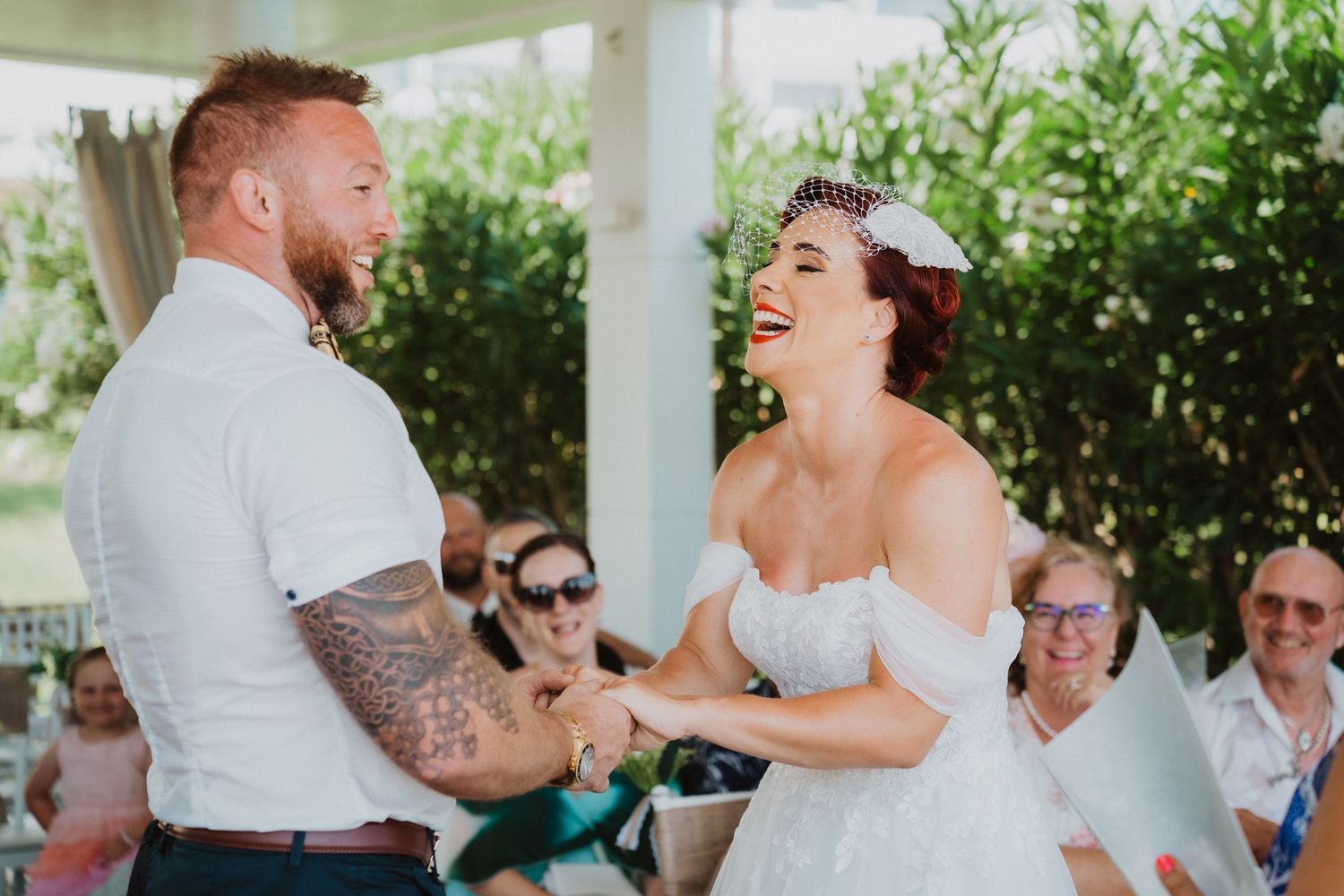 Wedding ceremony moment at outdoor covered venue with tropical background.