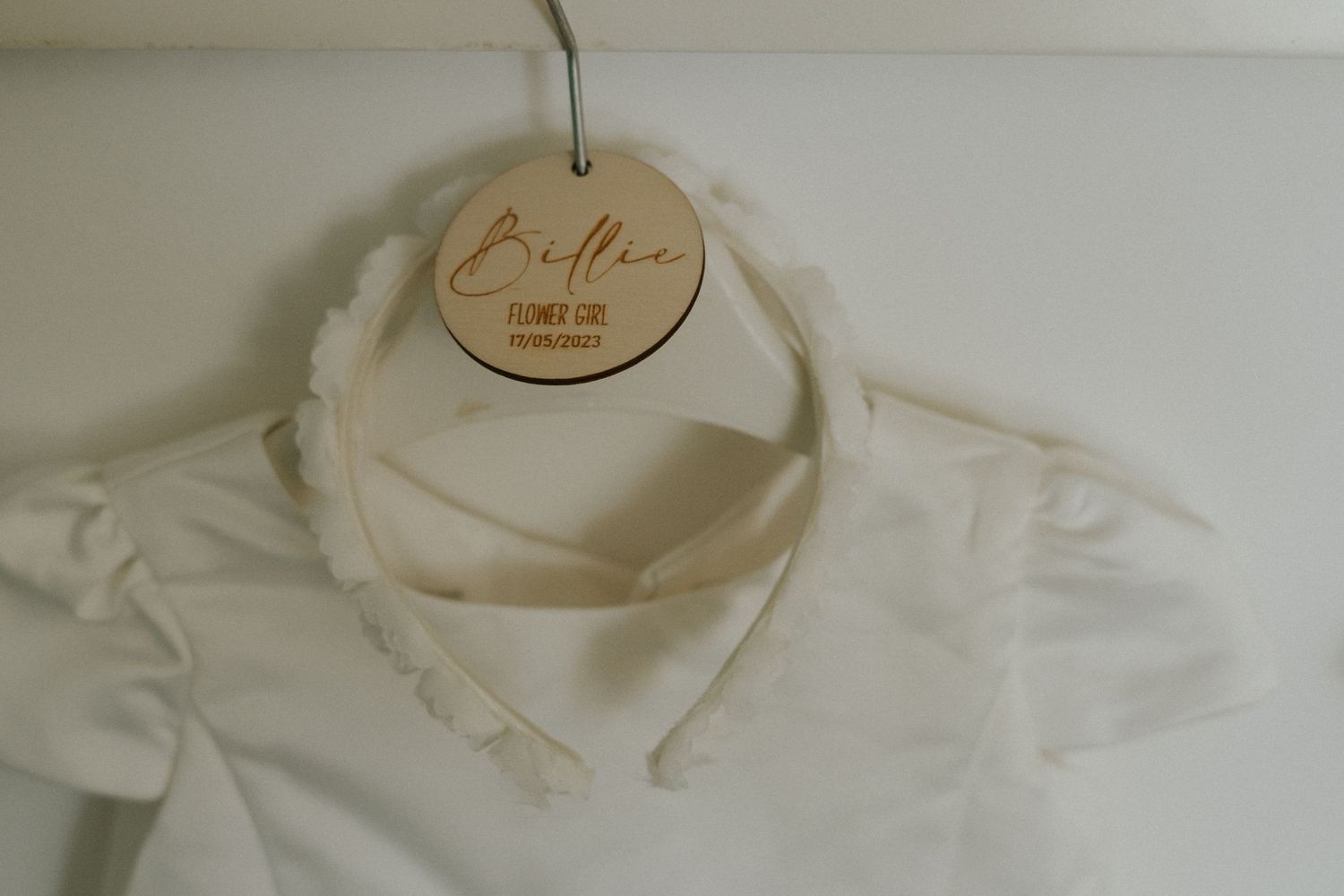 White dress collar detail with wooden hanger displaying 'Bella' text.