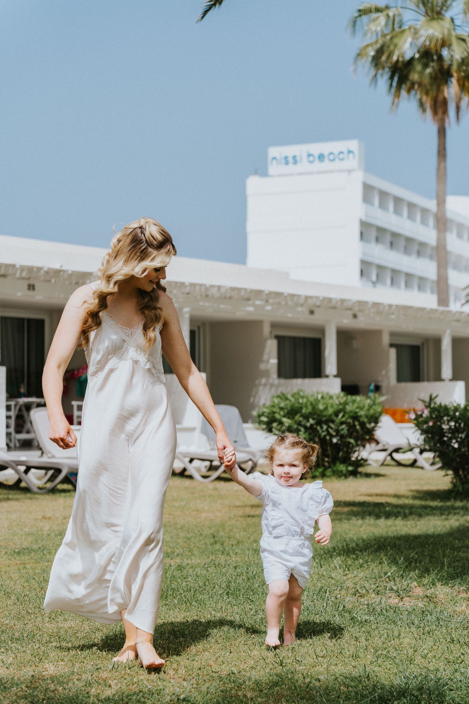 Elegant scene at a Mediterranean resort with palm trees and white architecture.
