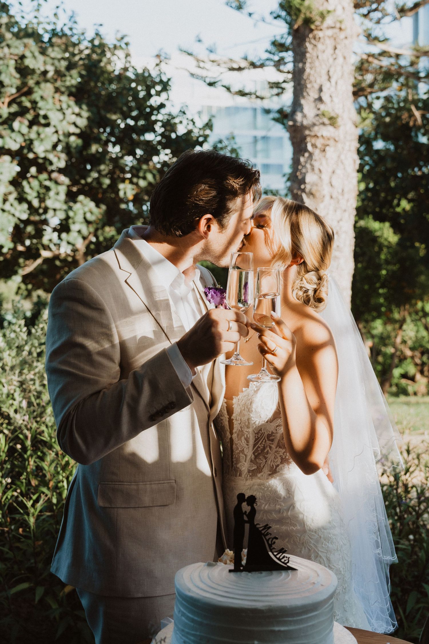 Bride and groom share champagne during their outdoor wedding cake cutting ceremony.