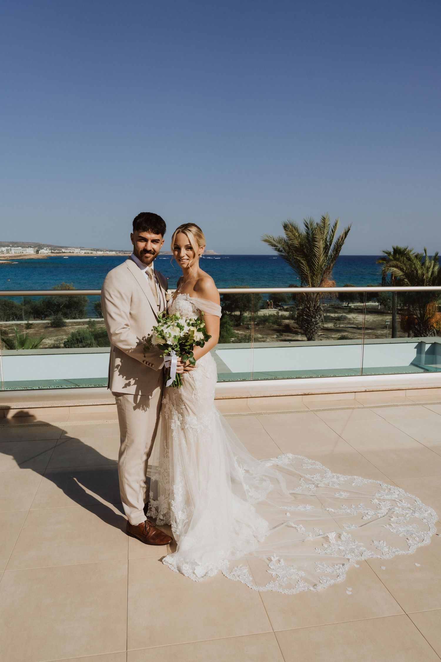 Wedding couple sharing romantic moments on an oceanfront terrace with flowing white dress.