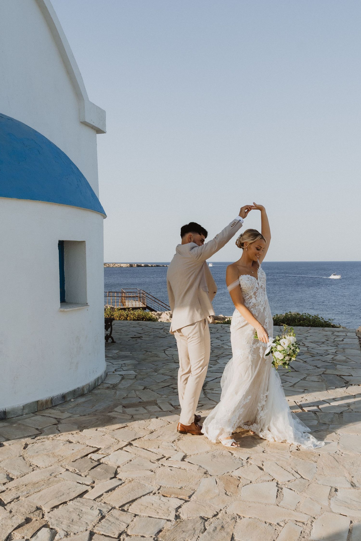 Couple dances on seaside terrace with white walls and ocean views.