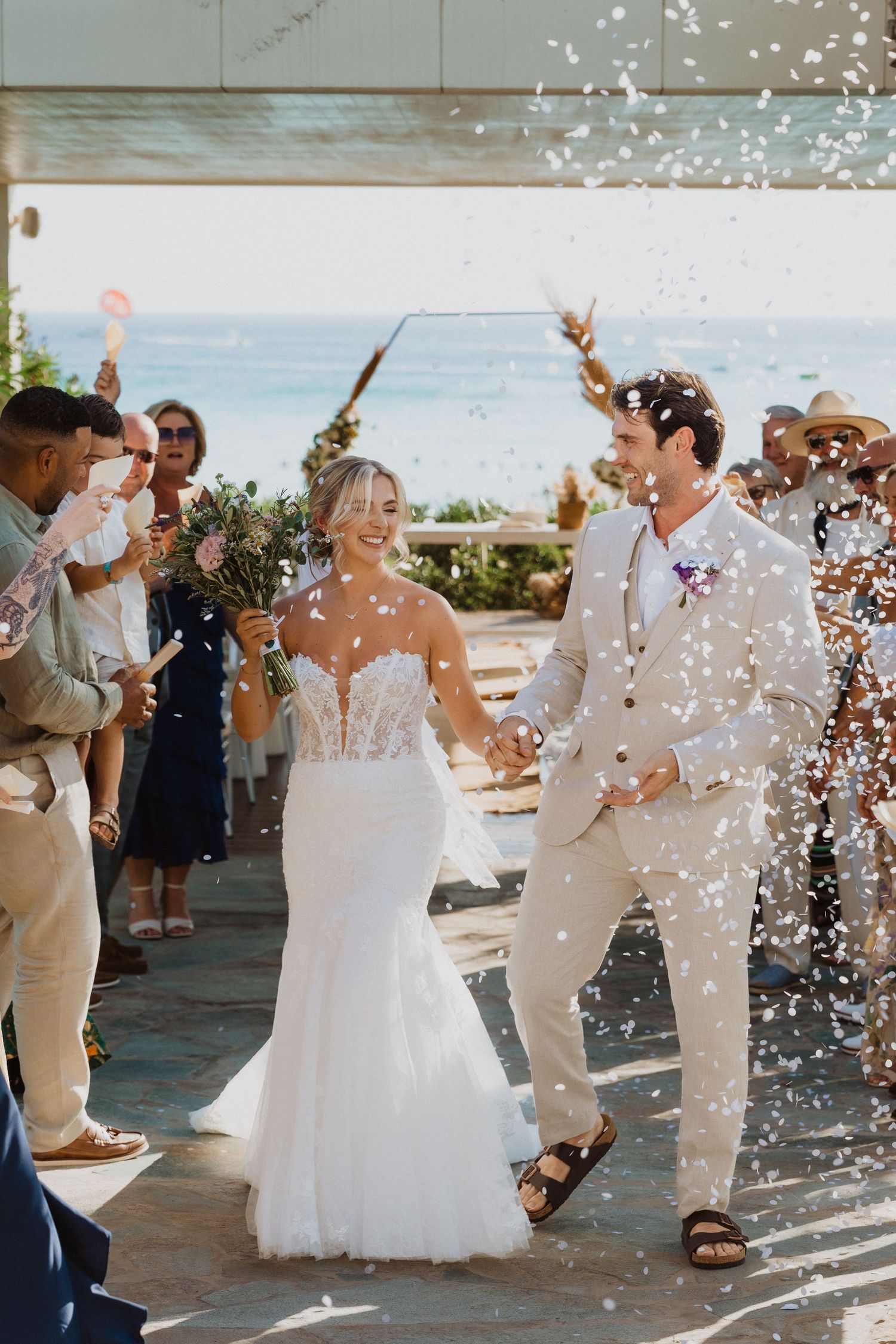 Sunlit wedding celebration with confetti shower and celebrating guests.