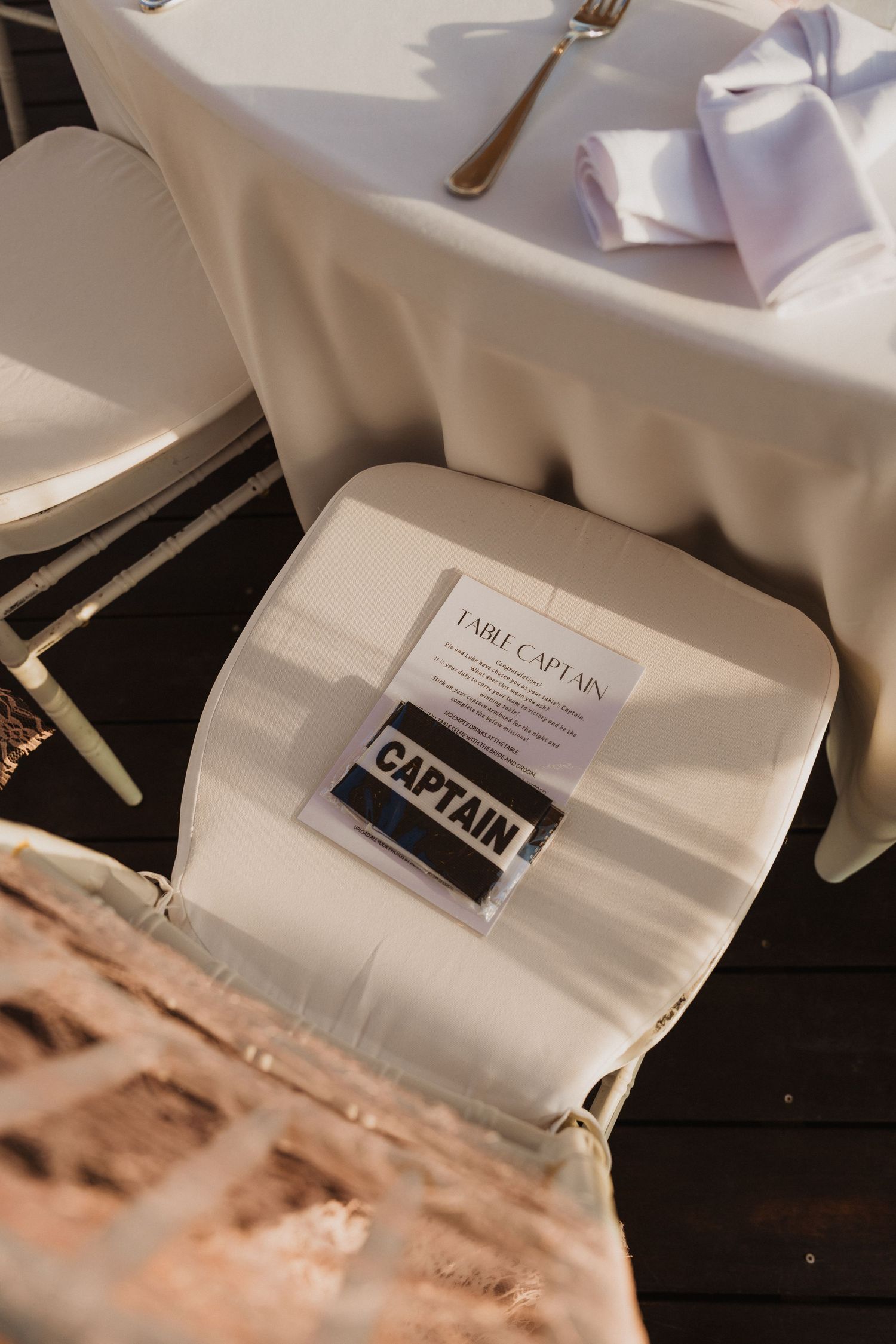 White table settings with folded napkins and place cards at an elegant reception.