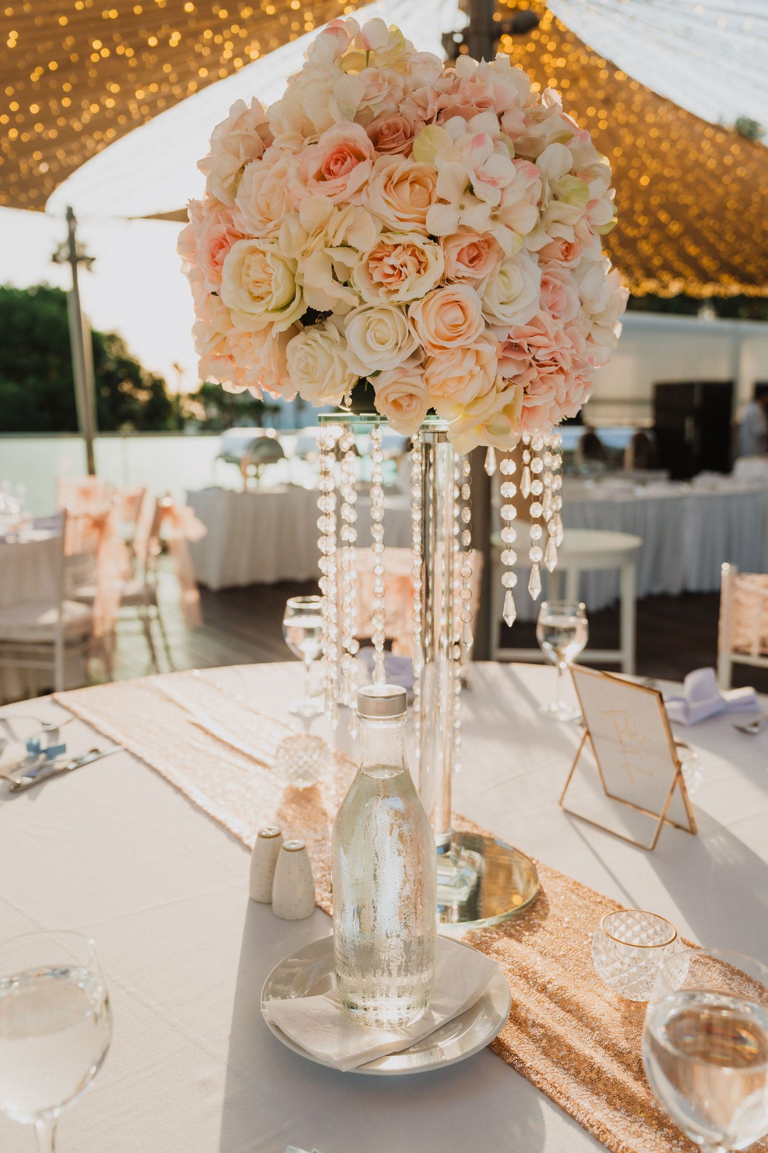 Wedding table settings with blush floral centerpieces, crystal accents, and gold sequin table runners.