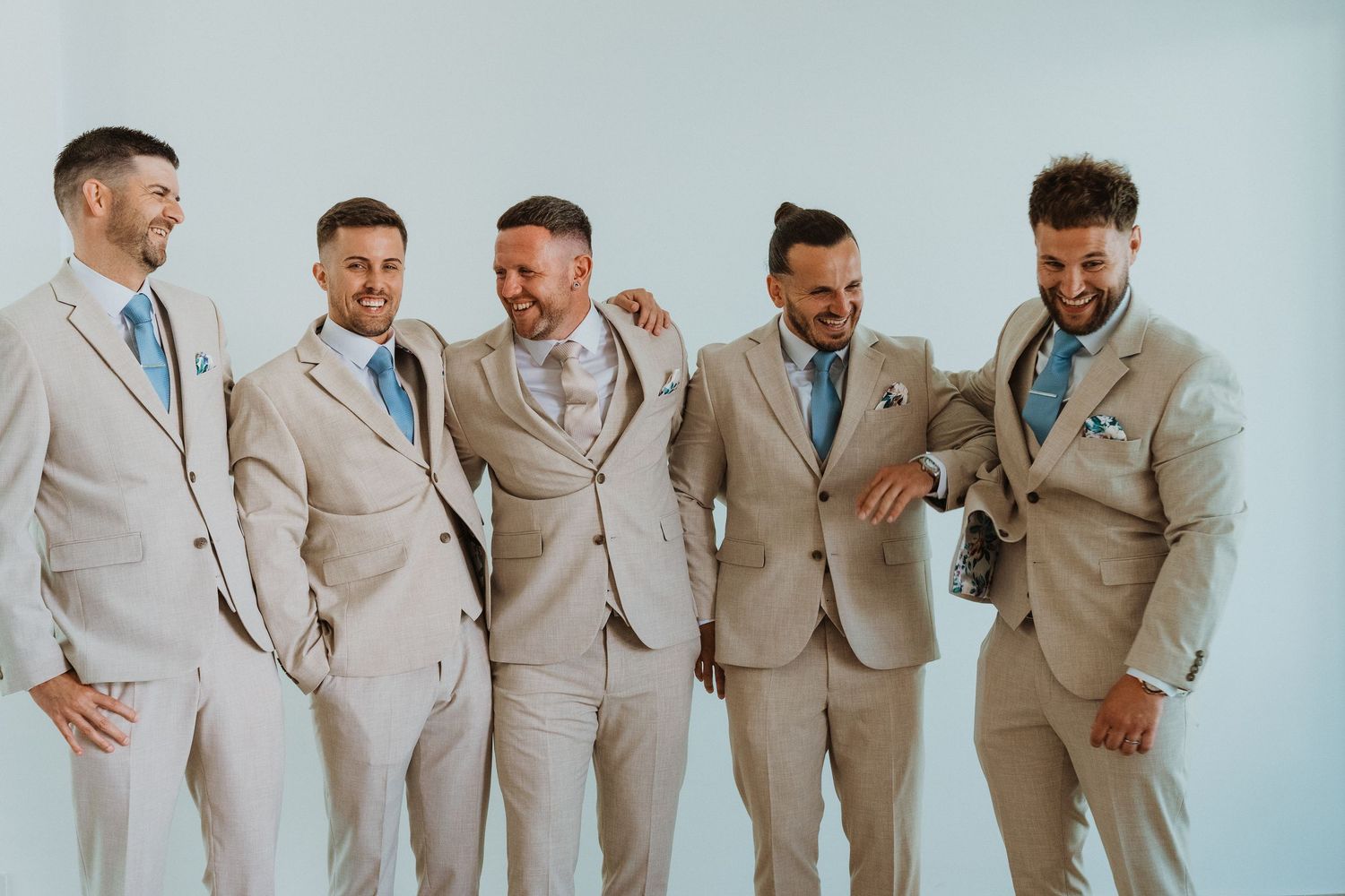 Groomsmen in beige suits share a candid laughing moment in a sequence of wedding party photos.