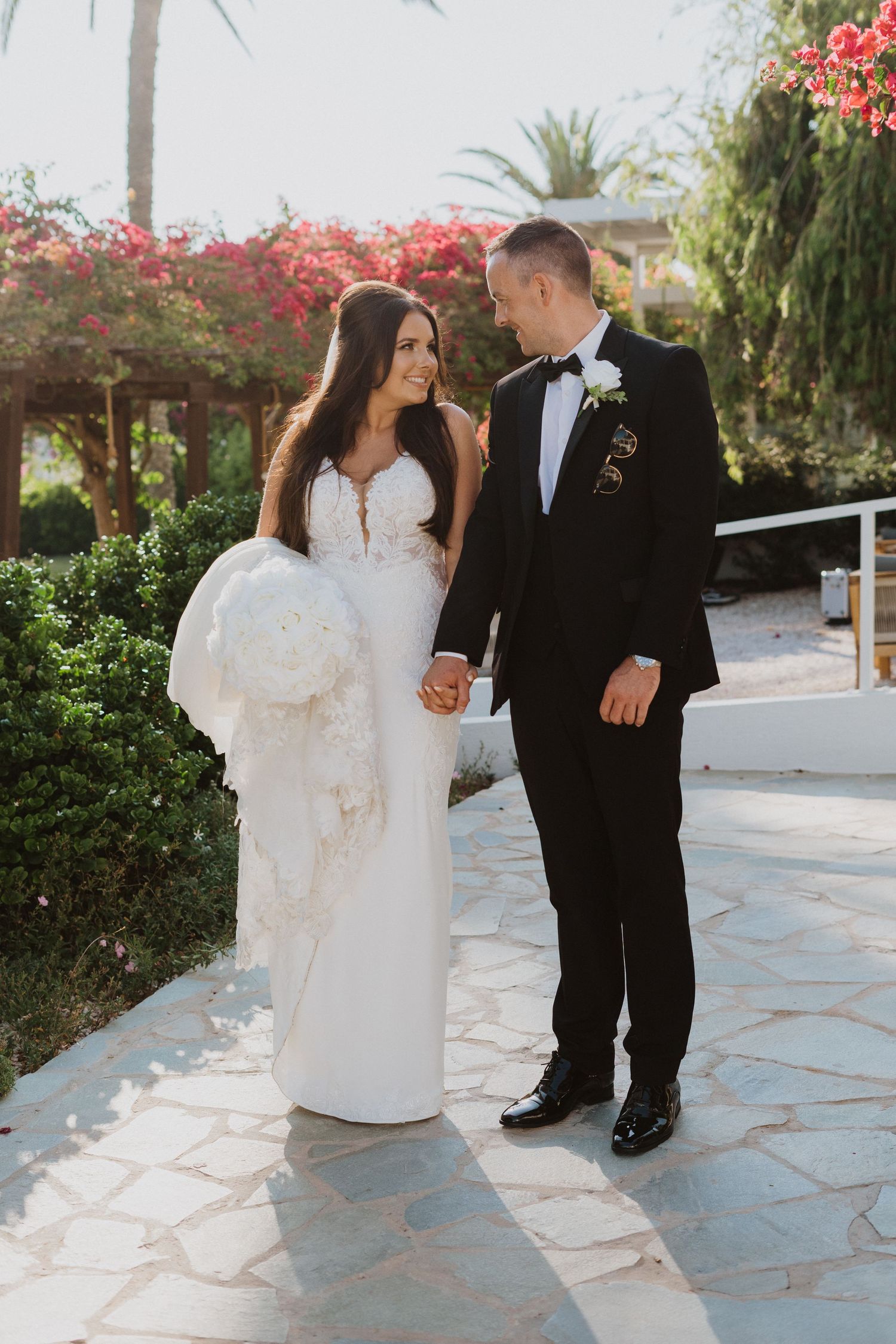 Bride and groom share intimate moments on a stone patio surrounded by tropical landscaping.