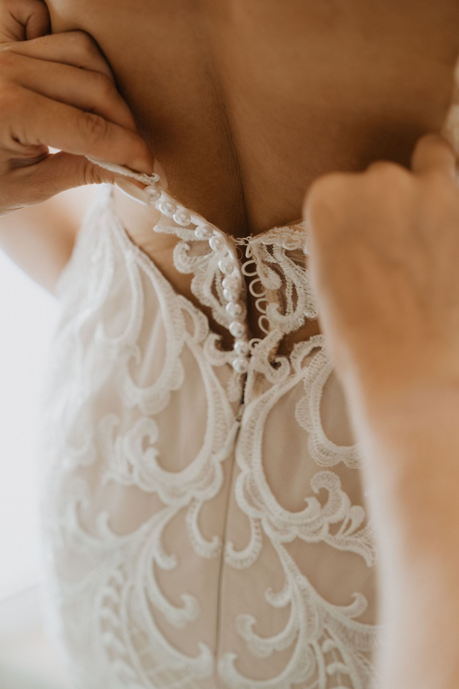 Close-up detail of delicate white lace embroidery on a wedding dress with intricate floral and swirl patterns.