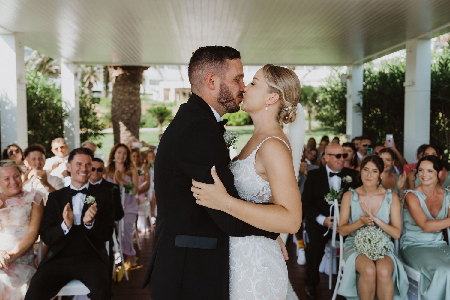 Couple shares their first dance under covered pavilion at outdoor wedding.