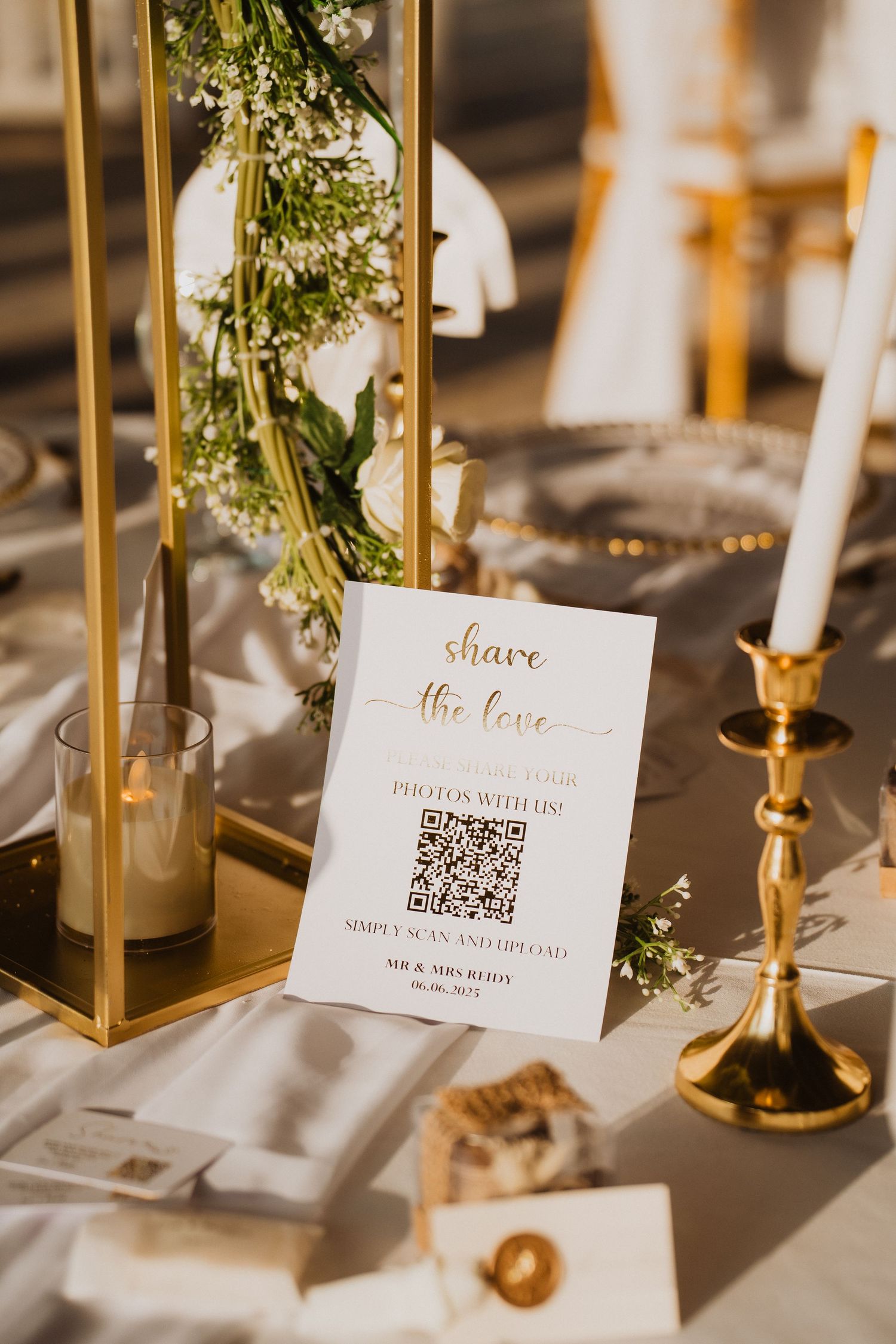 Elegant gold wedding table decor with QR code share the love sign and white candles.