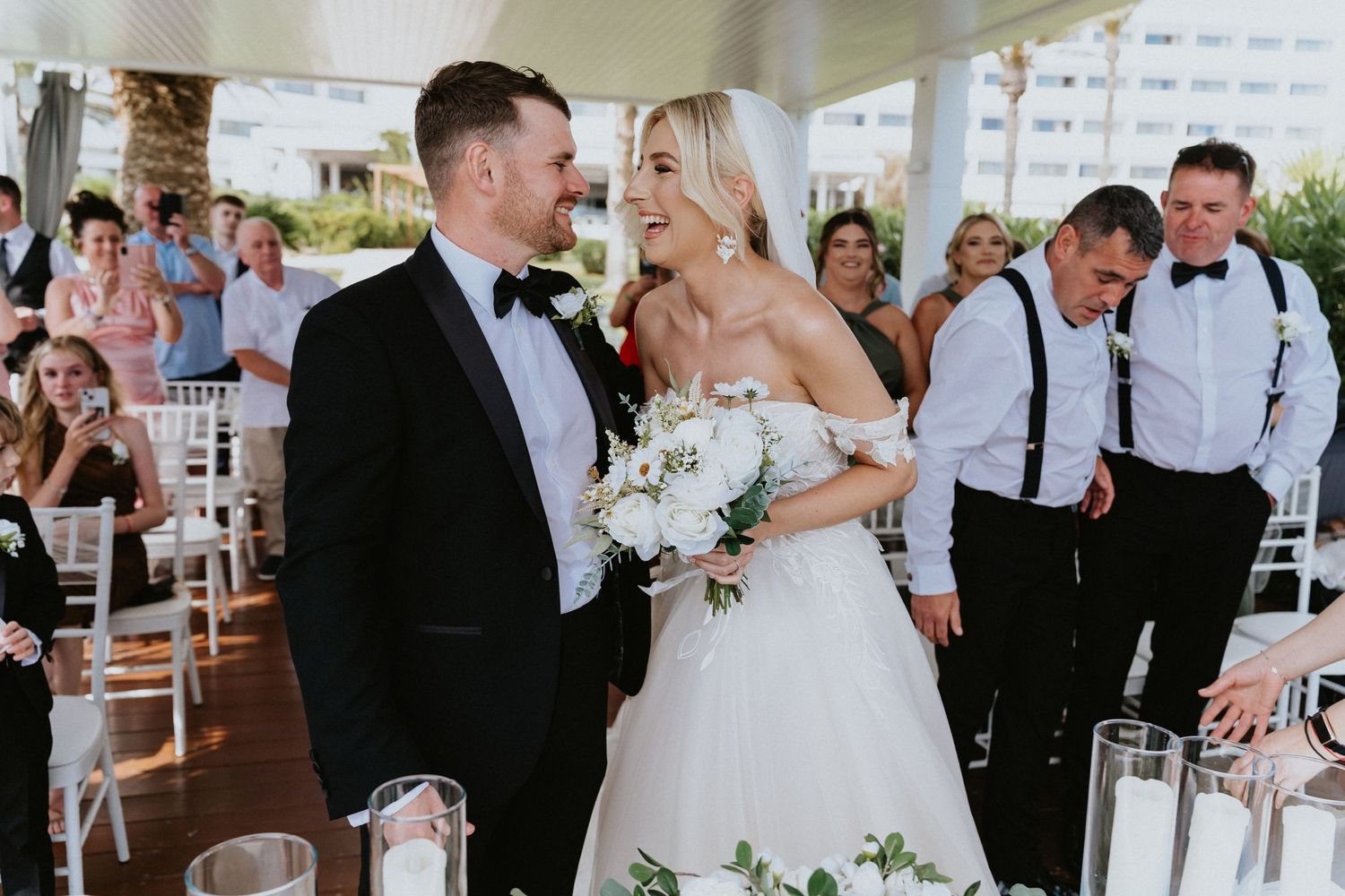 Elegant wedding celebration on covered patio with formal attire and white decor.