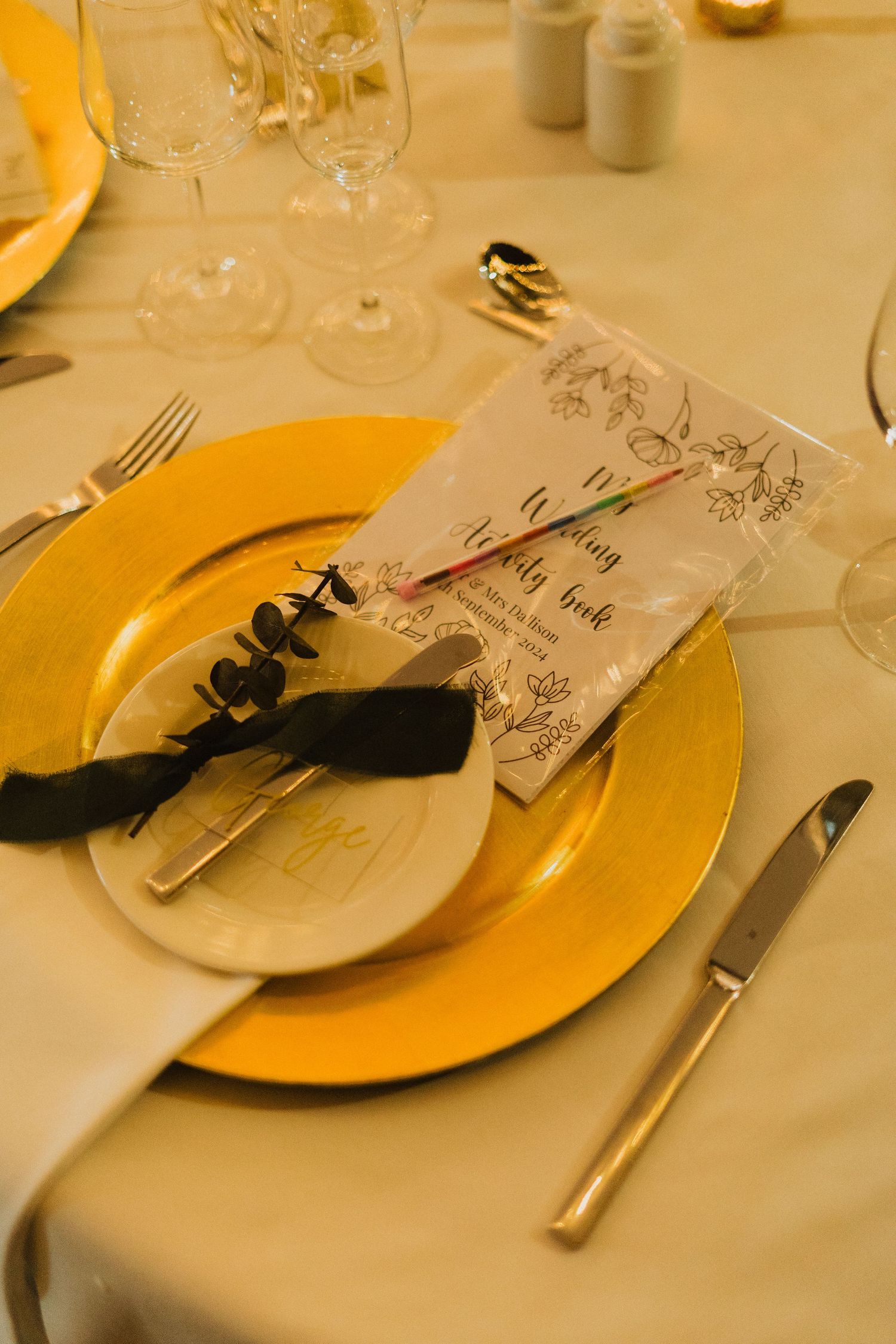 Table setting with yellow plate, cutlery and menu card decorated with a black bow at an elegant dinner event.
