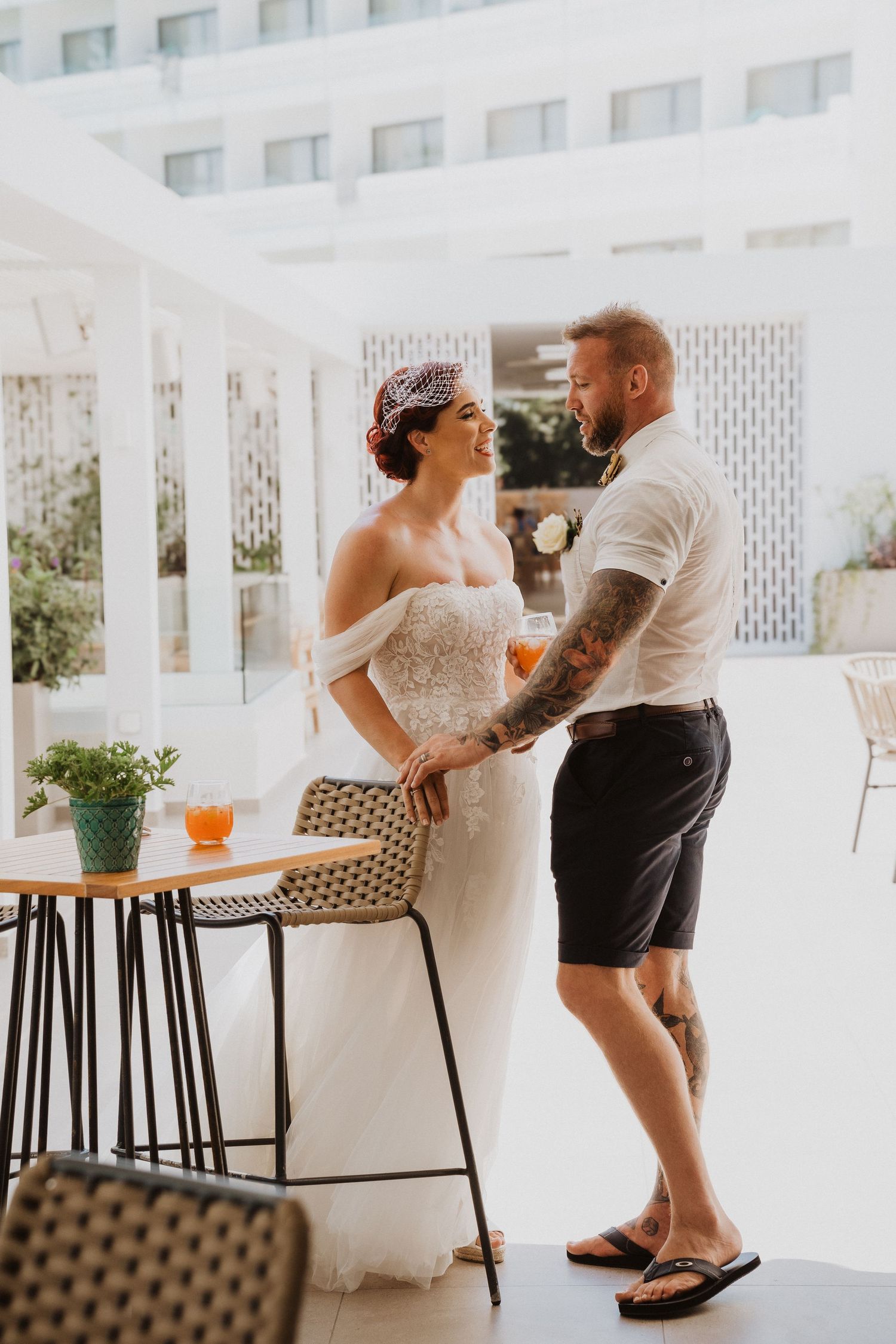 Wedding couple in casual attire sharing an intimate moment in a bright indoor space.