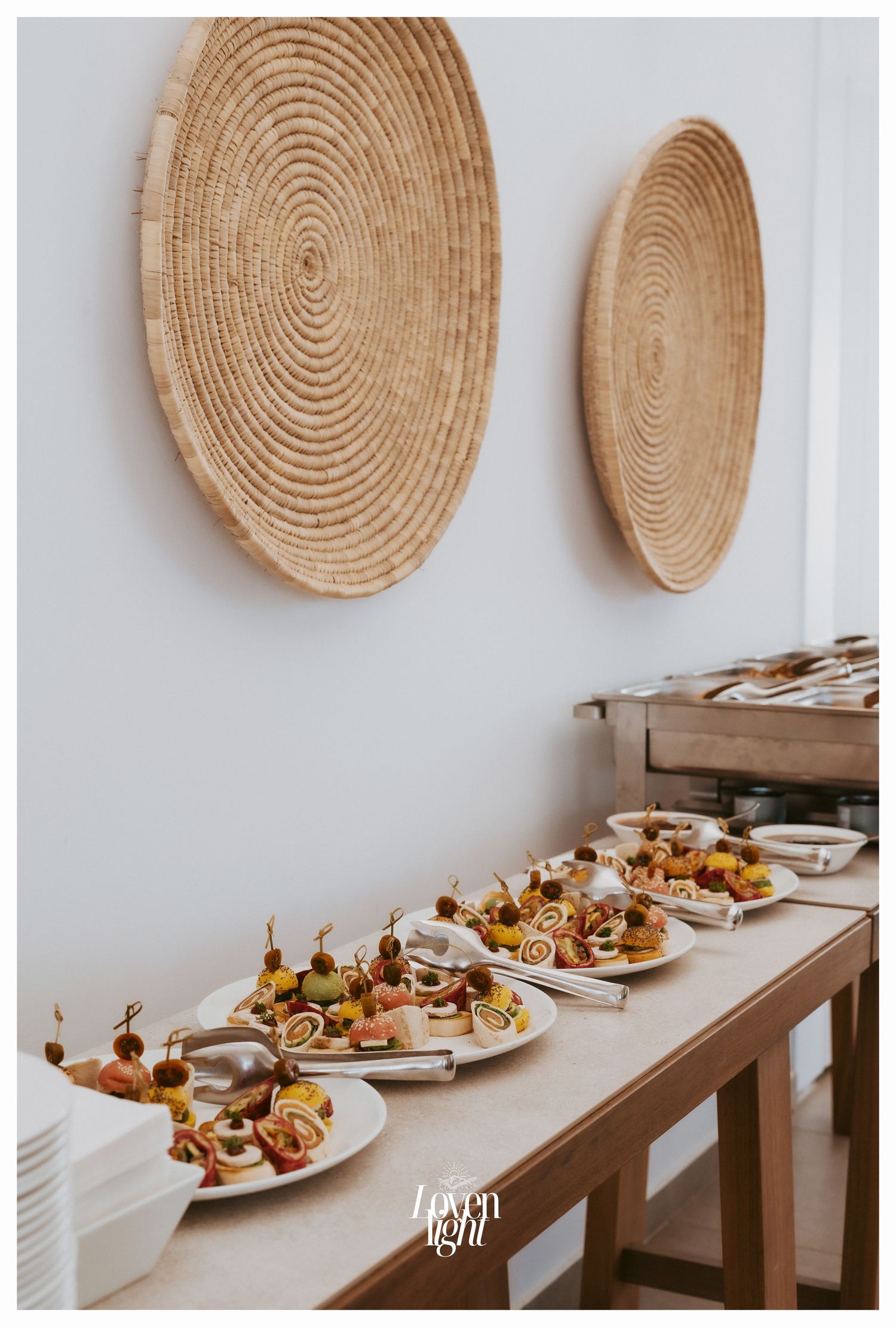 Appetizer plates lined up on a wooden table with decorative woven wall baskets displayed above.