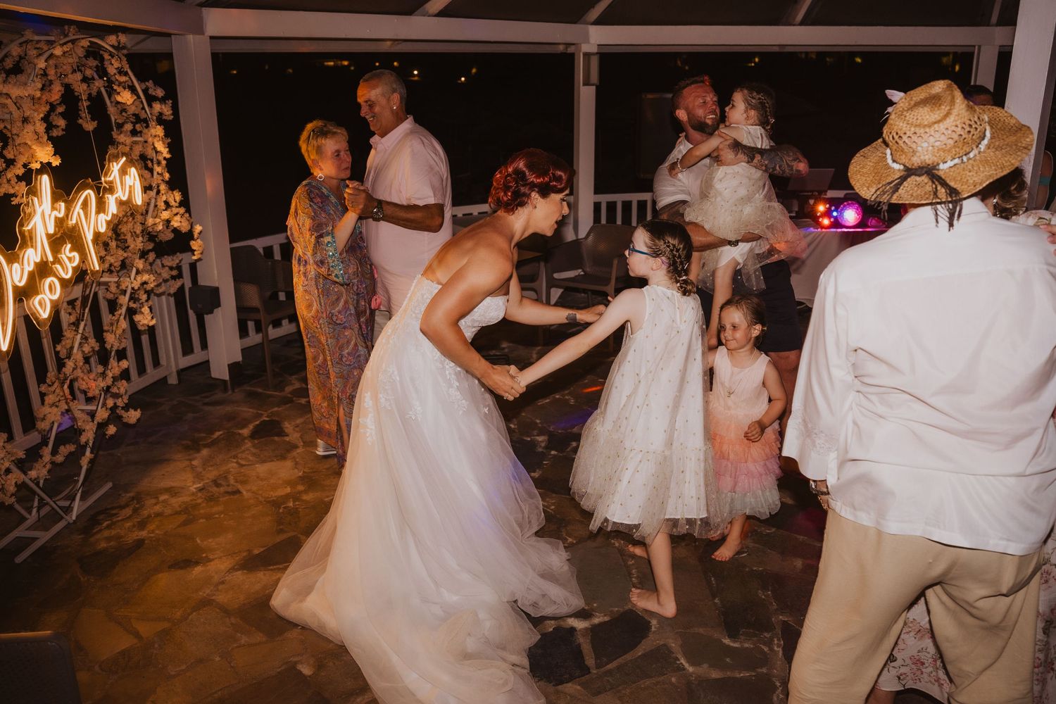 People dancing at an evening wedding reception on an illuminated patio.