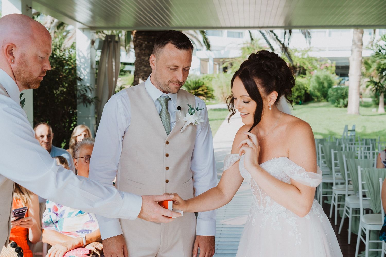 A couple shares an emotional moment during their outdoor wedding ceremony under a covered patio area.