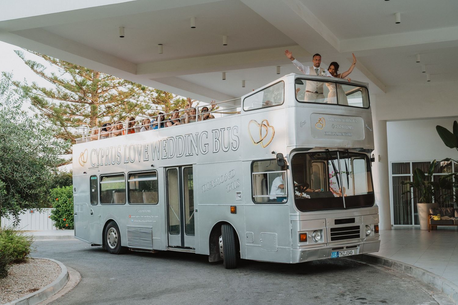 A white classic double-decker bus parked under a building overhang.