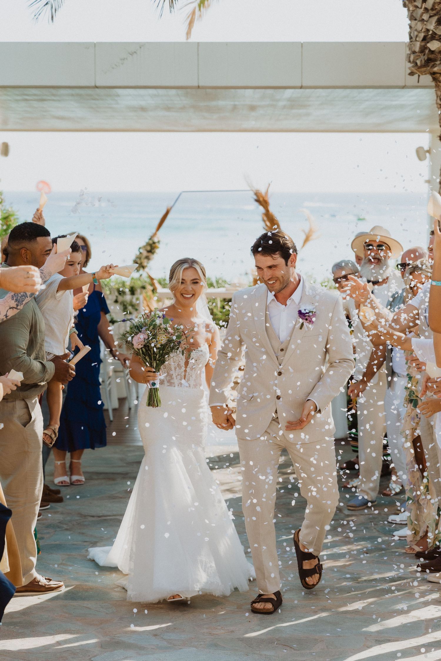 Confetti fills the air as wedding couple makes their grand exit through cheering guests.