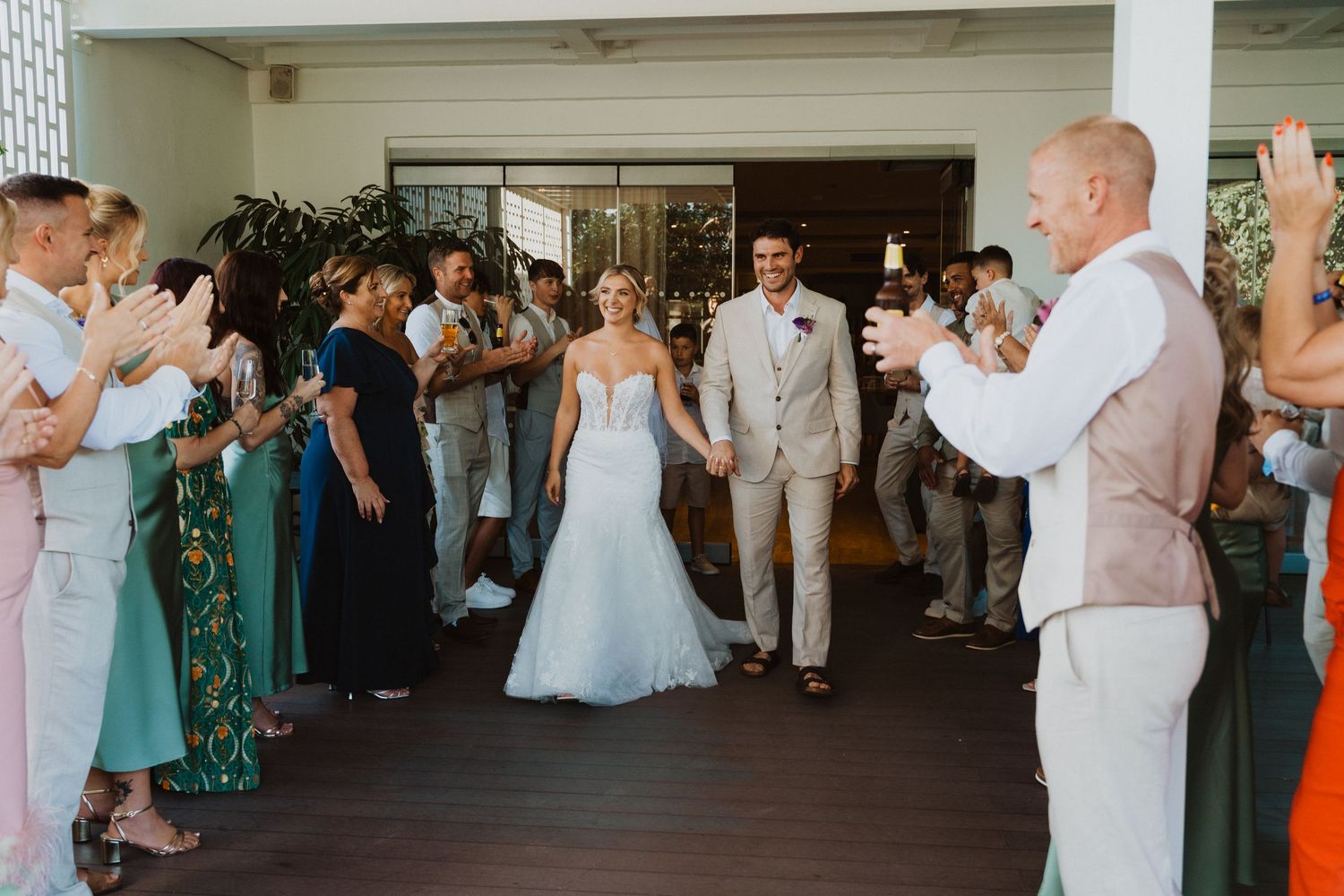 Wedding guests gather at an outdoor reception venue with light pink and green decor details.