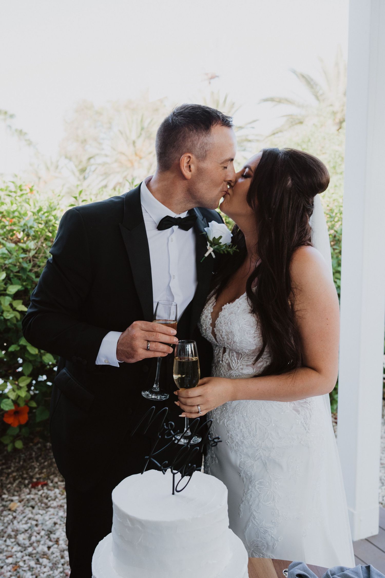 Wedding couple enjoys a romantic toast with champagne in a garden setting.