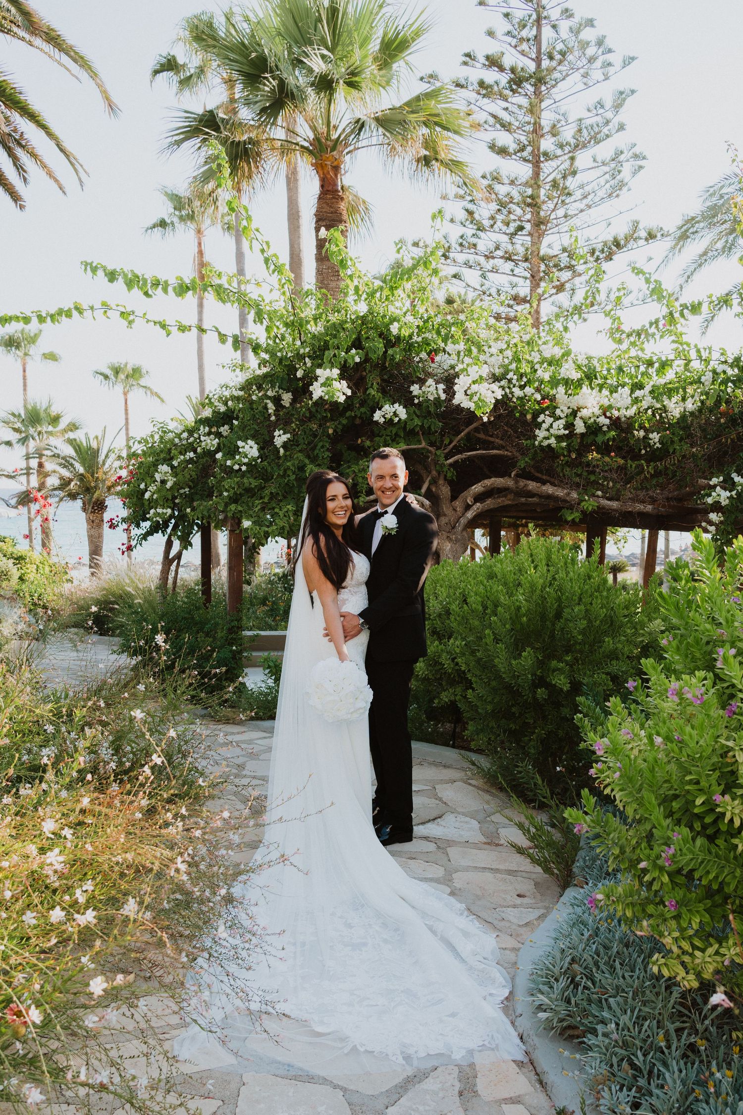 A joyful wedding moment captured on a stone pathway surrounded by tropical gardens.